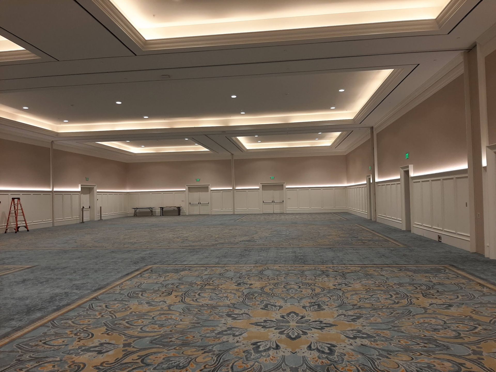 Empty, carpeted ballroom with decorative ceiling lights and walls.