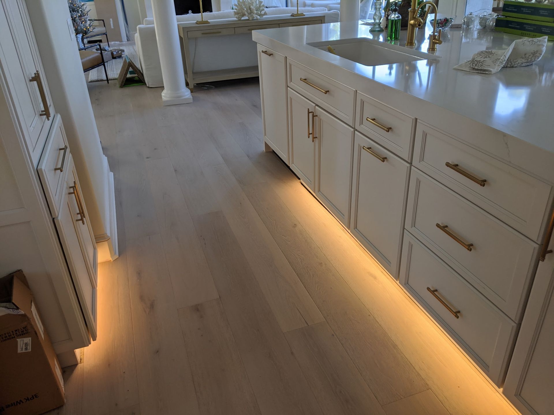 Kitchen with under-cabinet lighting; white cabinets and light wood flooring.