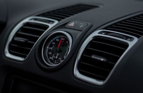 A close up of a car dashboard with a clock and air vents