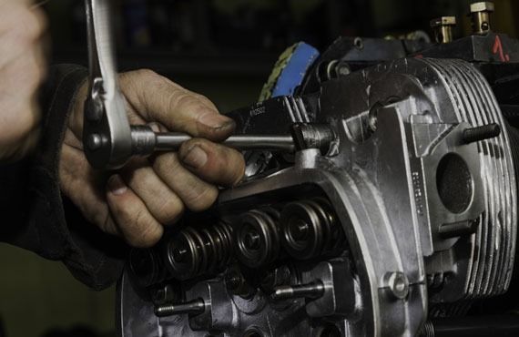 A man is working on a motorcycle engine with a wrench.