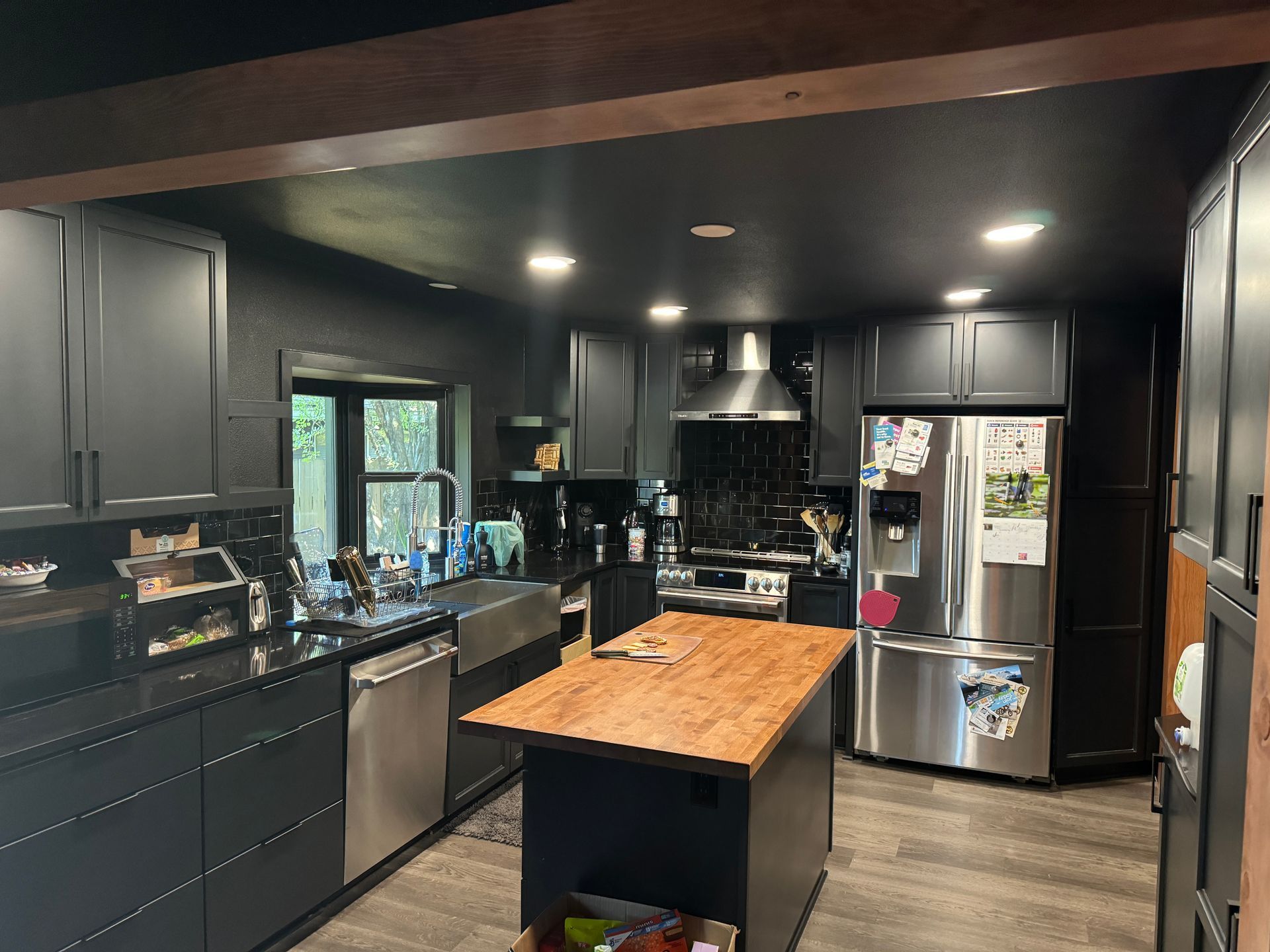 Modern kitchen with dark cabinets, black appliances, and a wooden island countertop