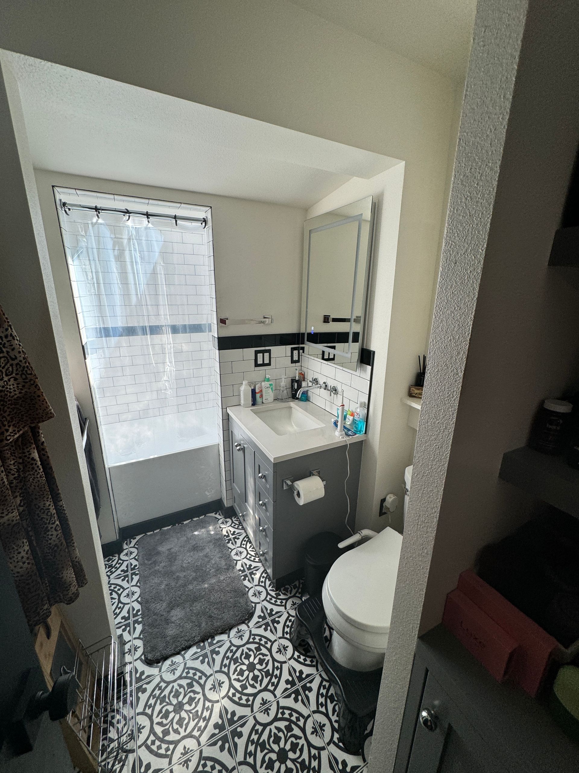 Small bathroom with patterned floor, shower curtain, sink, mirror, and toilet.
