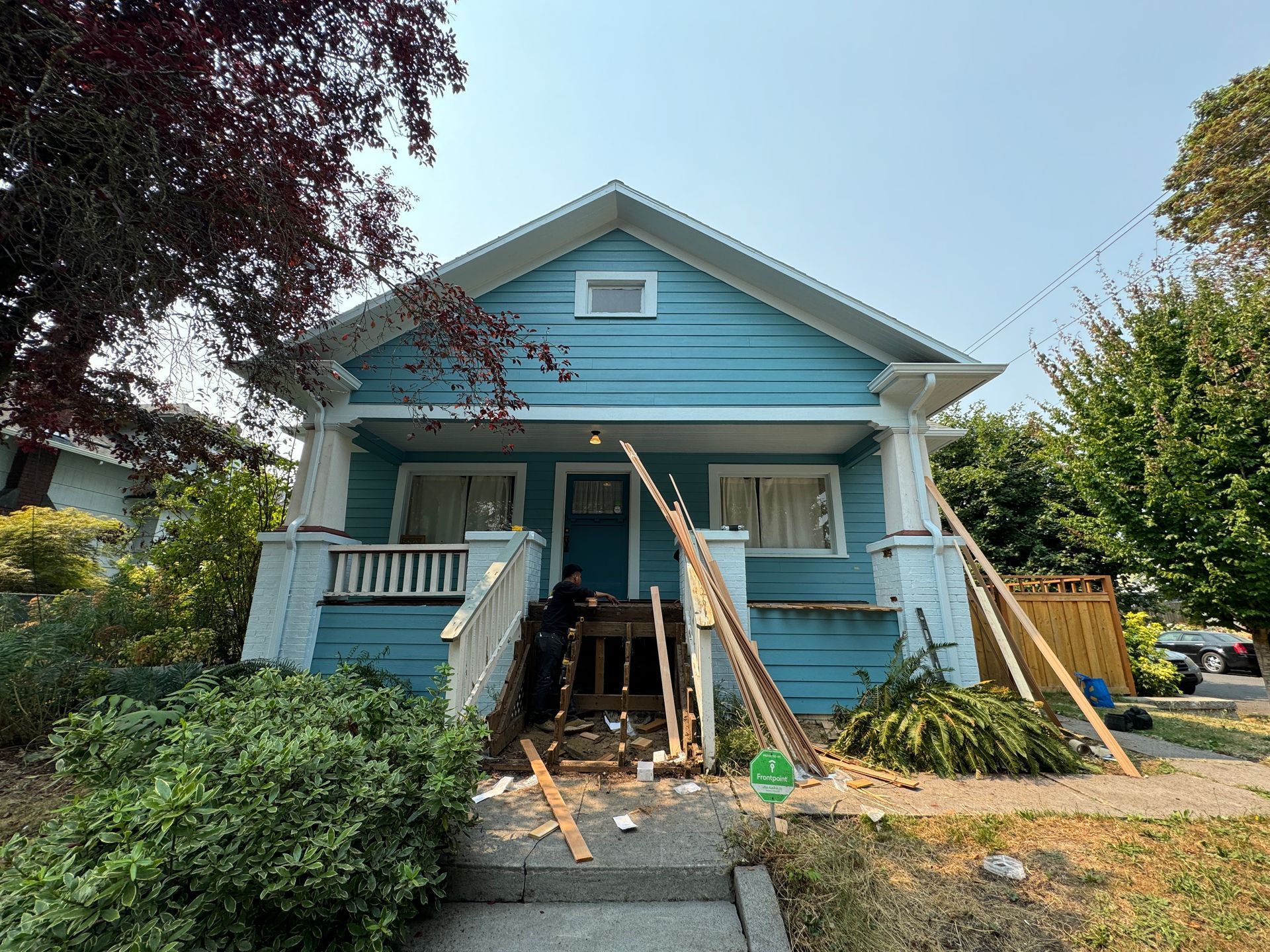 Blue house with porch under repair, debris and wooden supports at the front entrance