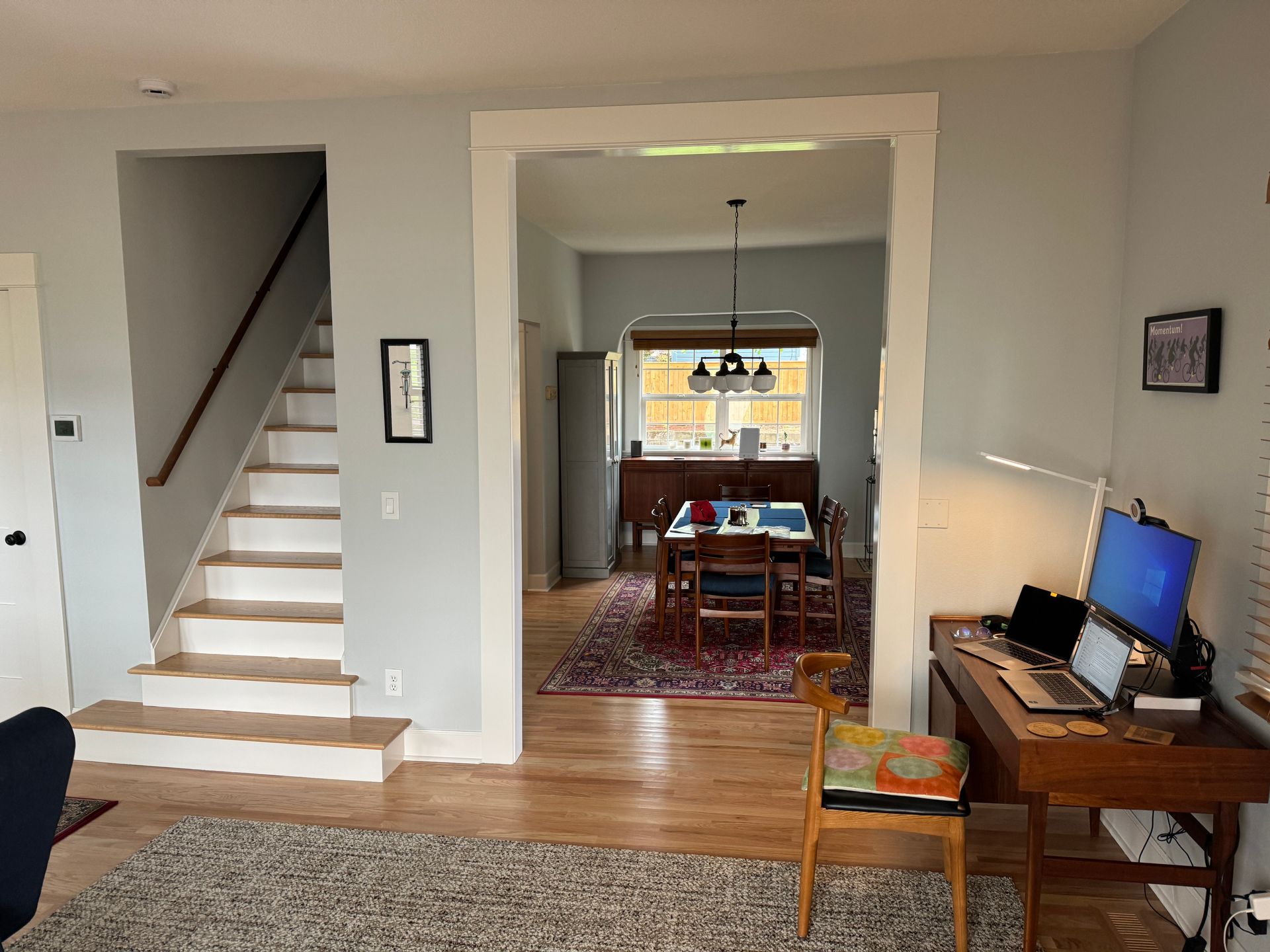 Living room opening to dining room, with staircase on the left and a TV stand on the right.