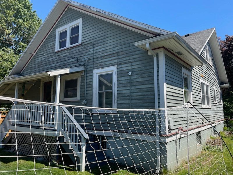 Gray house with white trim and a front porch ramp, viewed from the yard on a sunny day