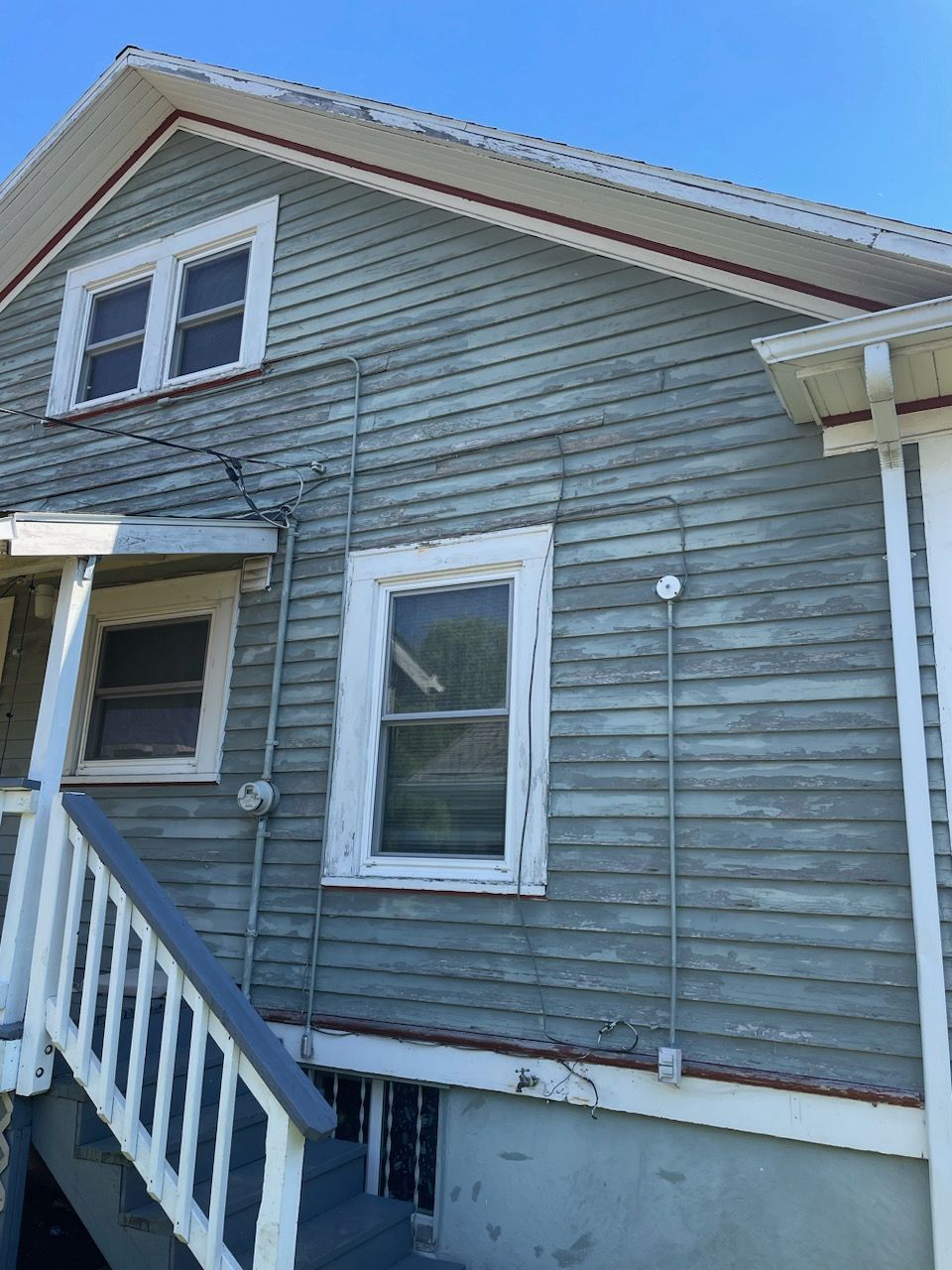 Gray house exterior with white trim, front stairs, and blue sky