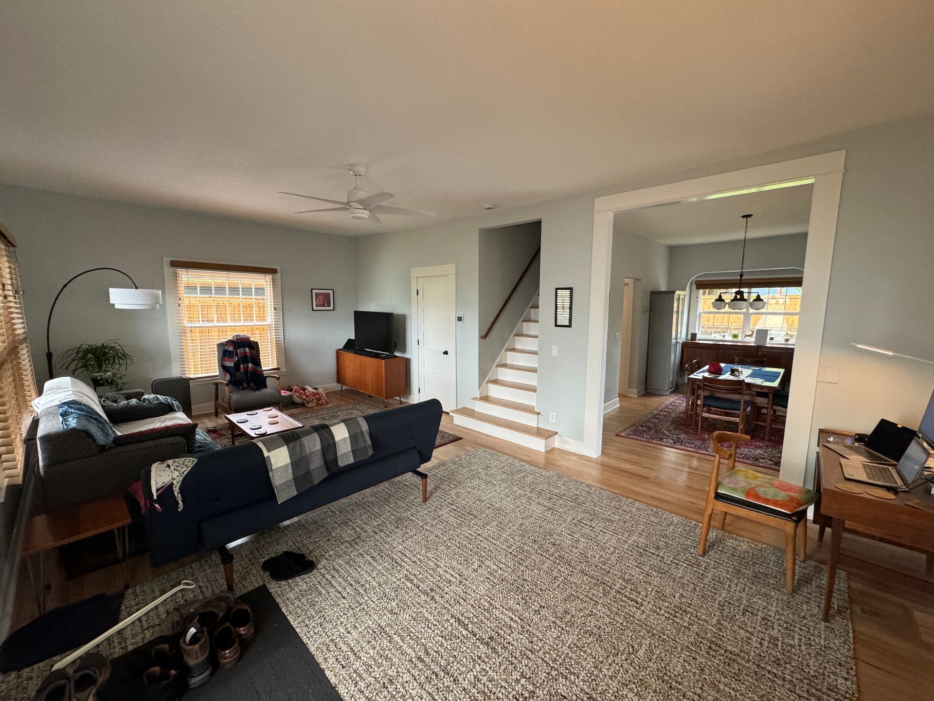 Spacious living room with gray walls, beige carpet, sectional sofa, and open view into a dining room and staircase