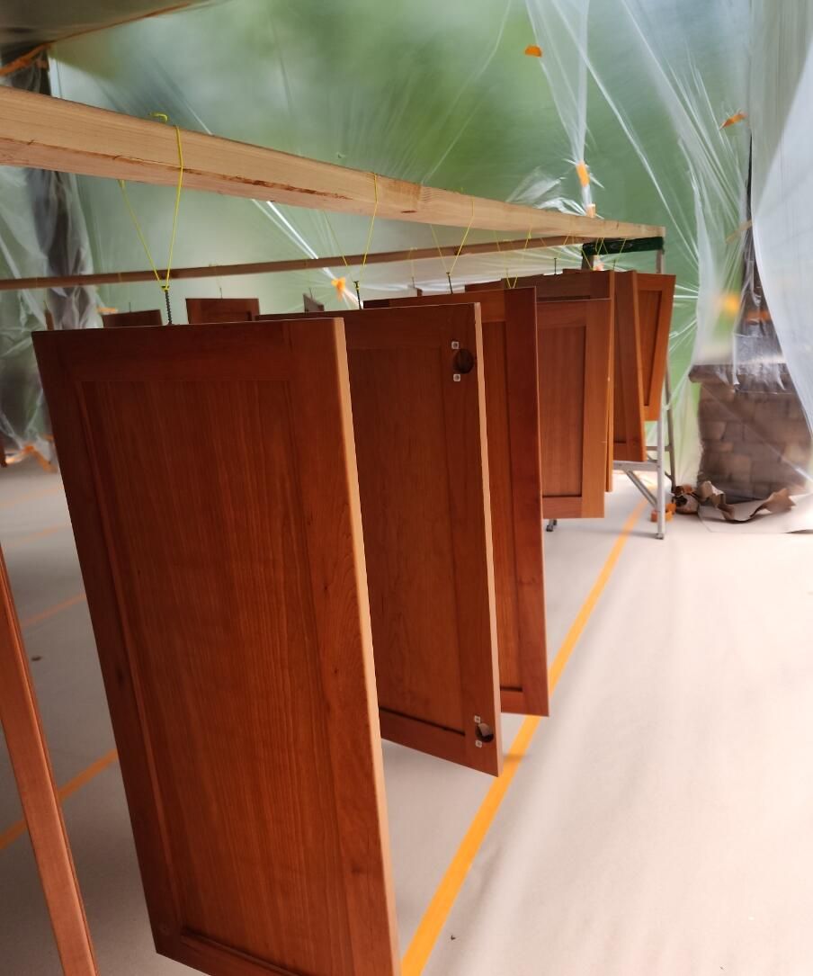 Wooden cabinet panels standing upright in a plastic-covered room during renovation