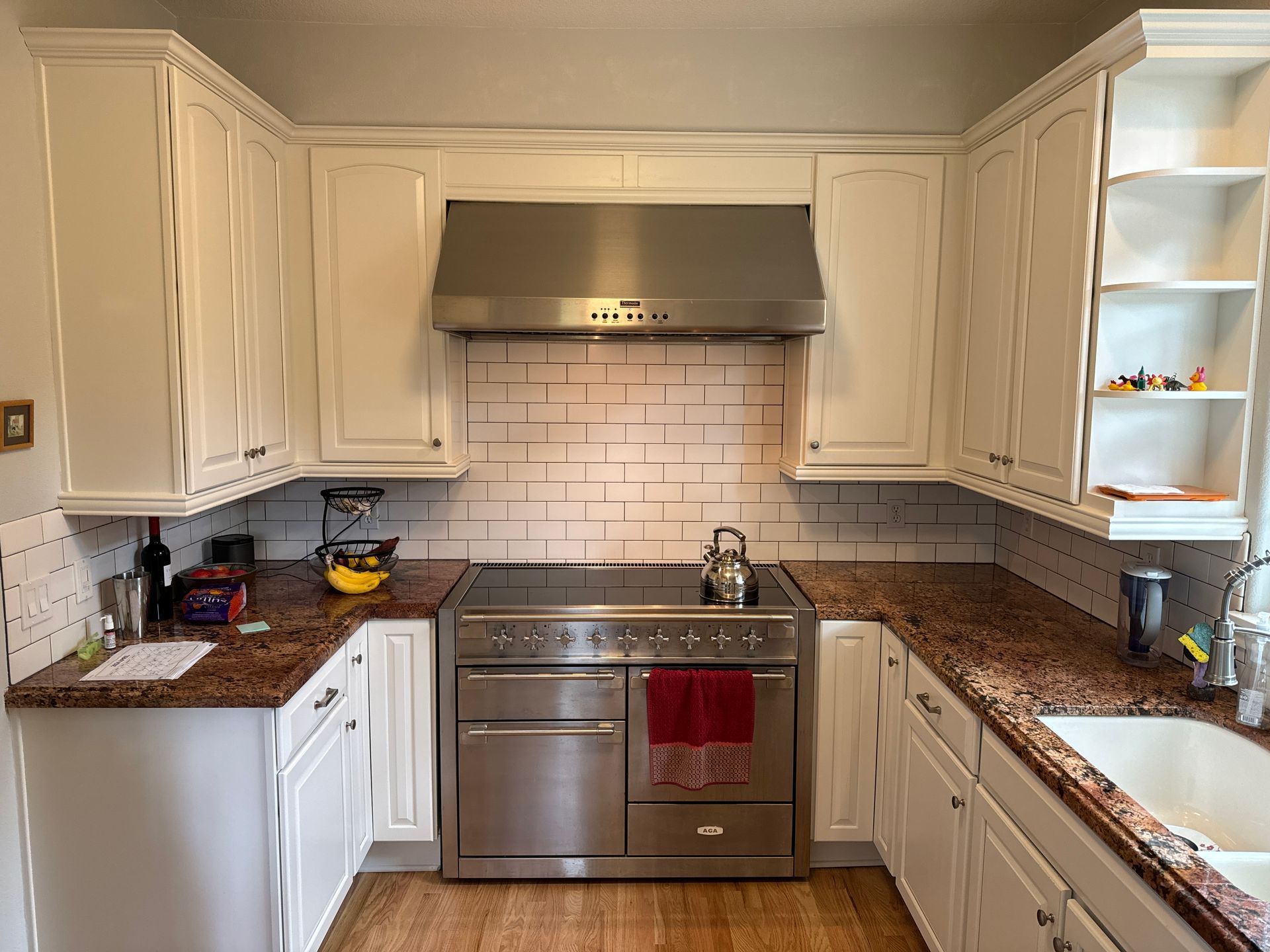 Bright white kitchen with stainless steel stove, granite counters, and tile backsplash