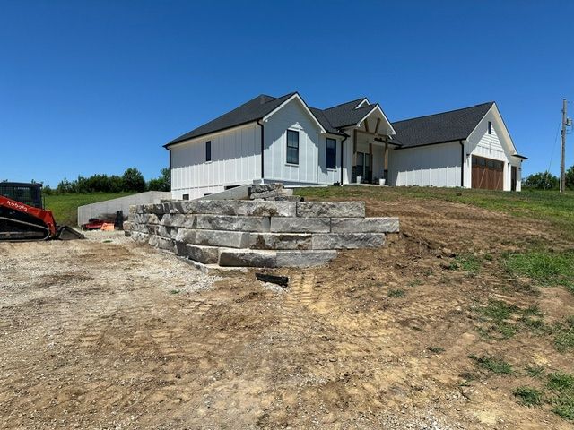 A large white house with a stone wall nearby