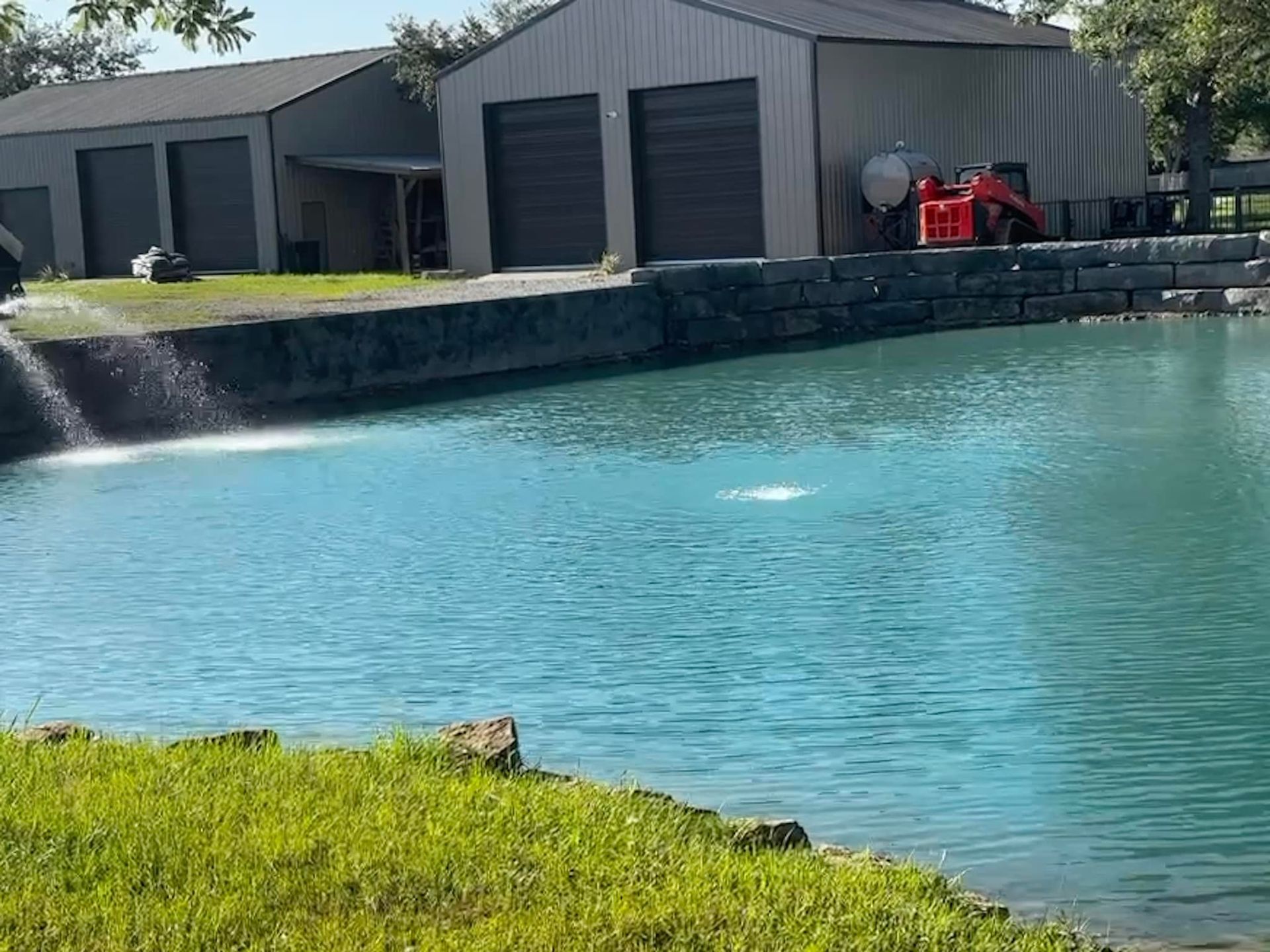 A pond with a waterfall in front of a building.