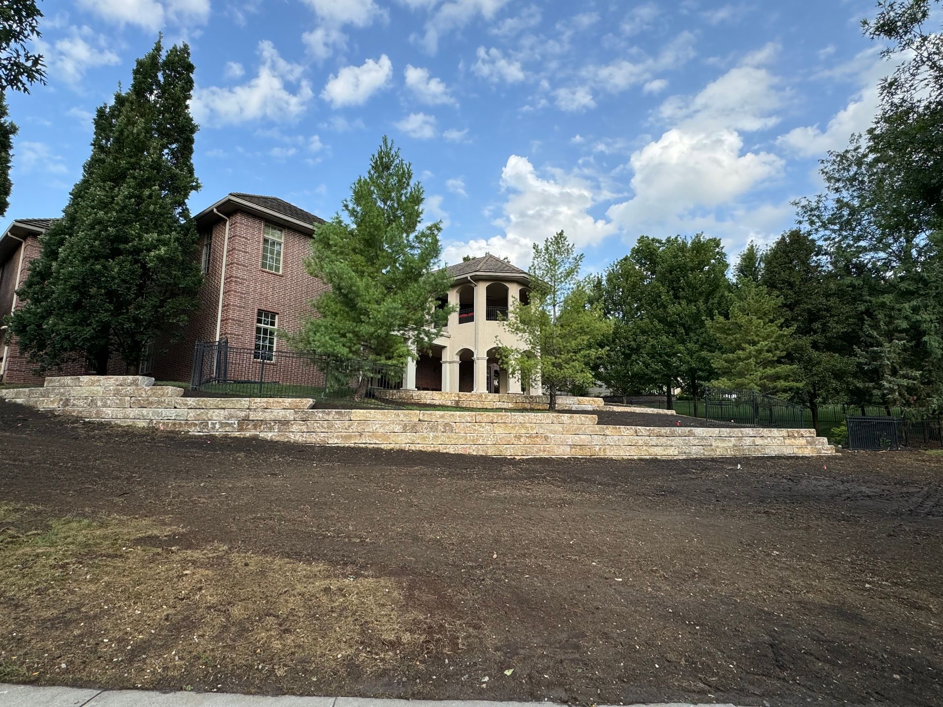 A large house sits on top of a hill surrounded by trees