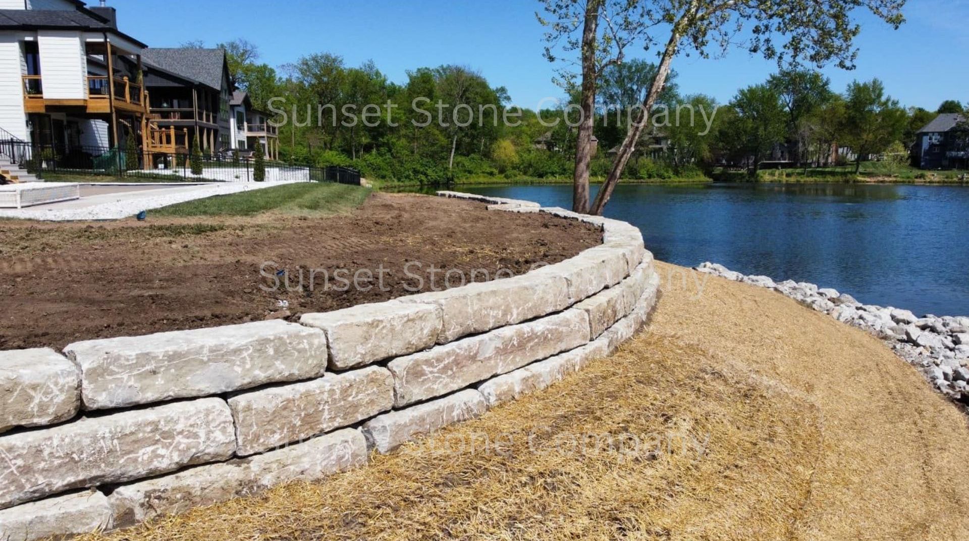 A stone wall is being built next to a body of water