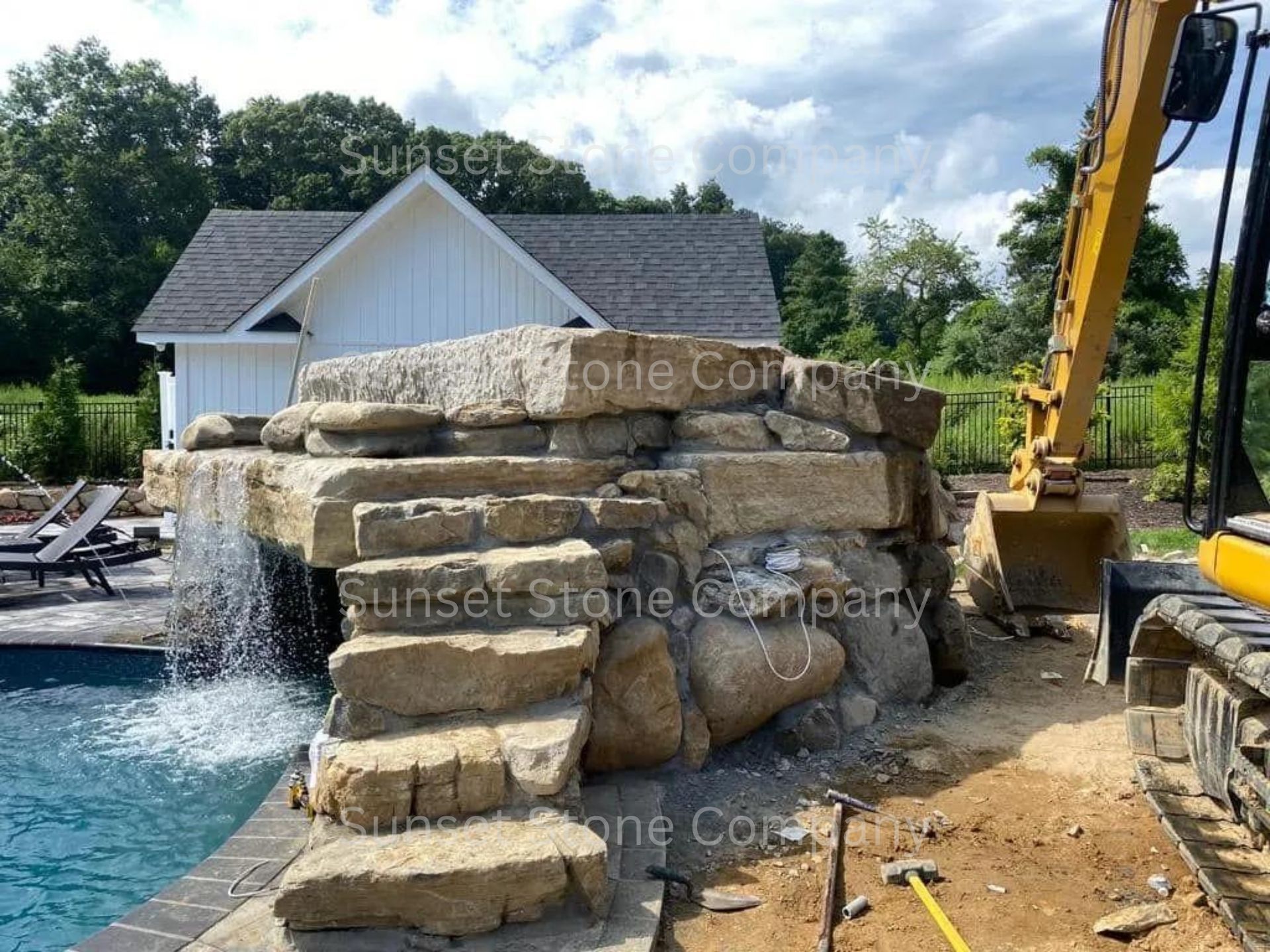 A large rock wall is being built next to a swimming pool