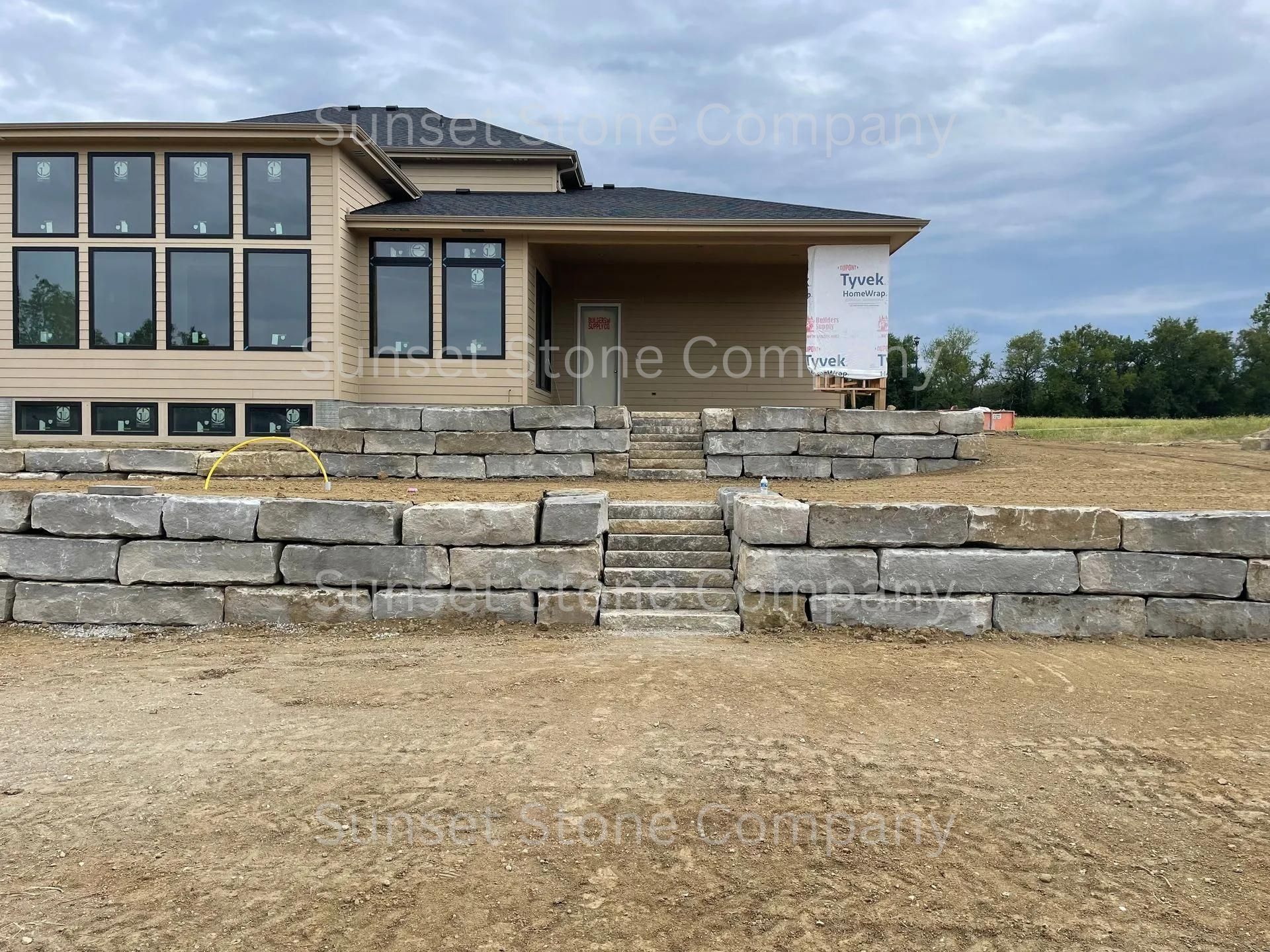 A house under construction with a stone wall in front of it