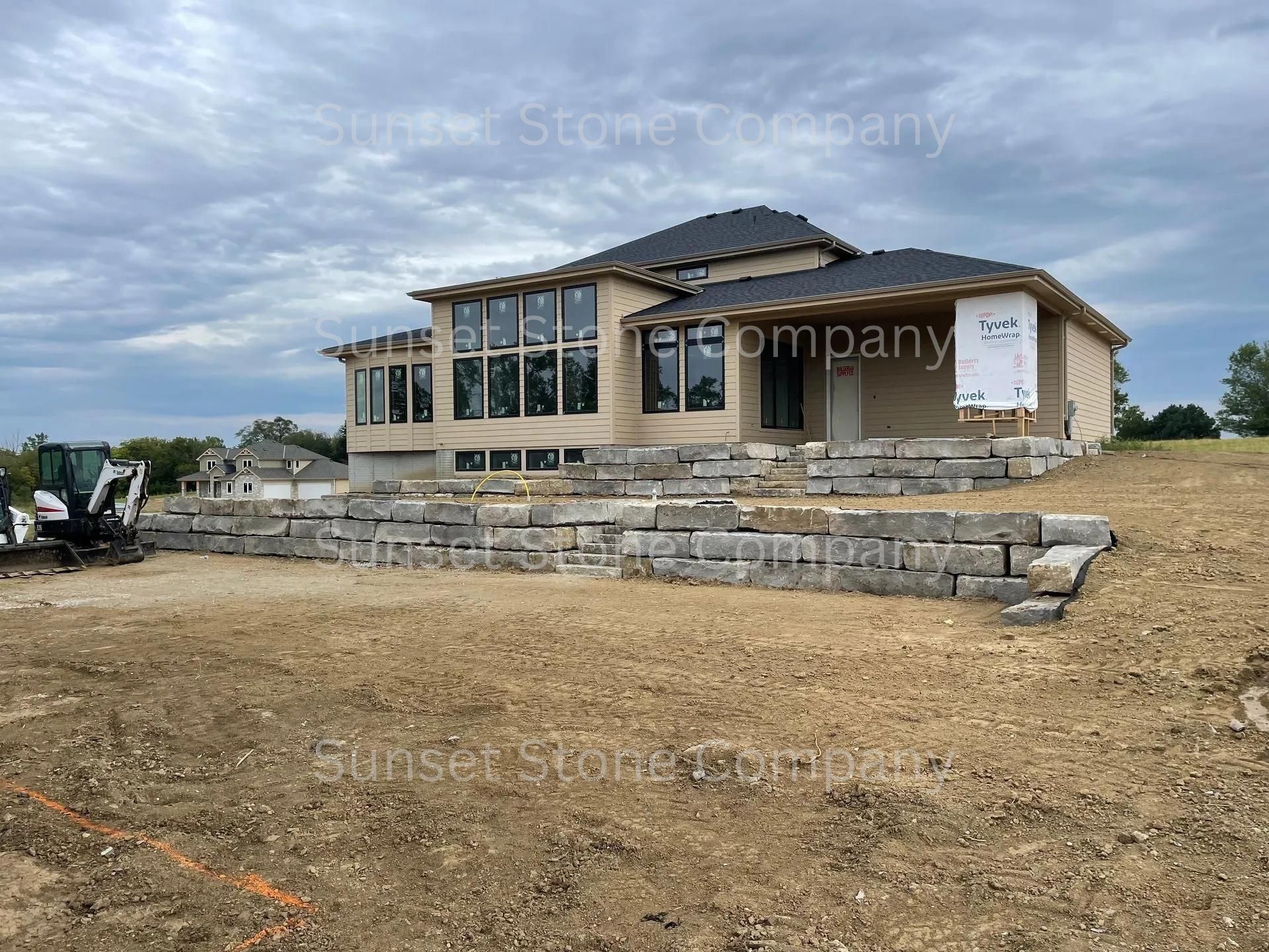 A large house is being built on top of a dirt hill