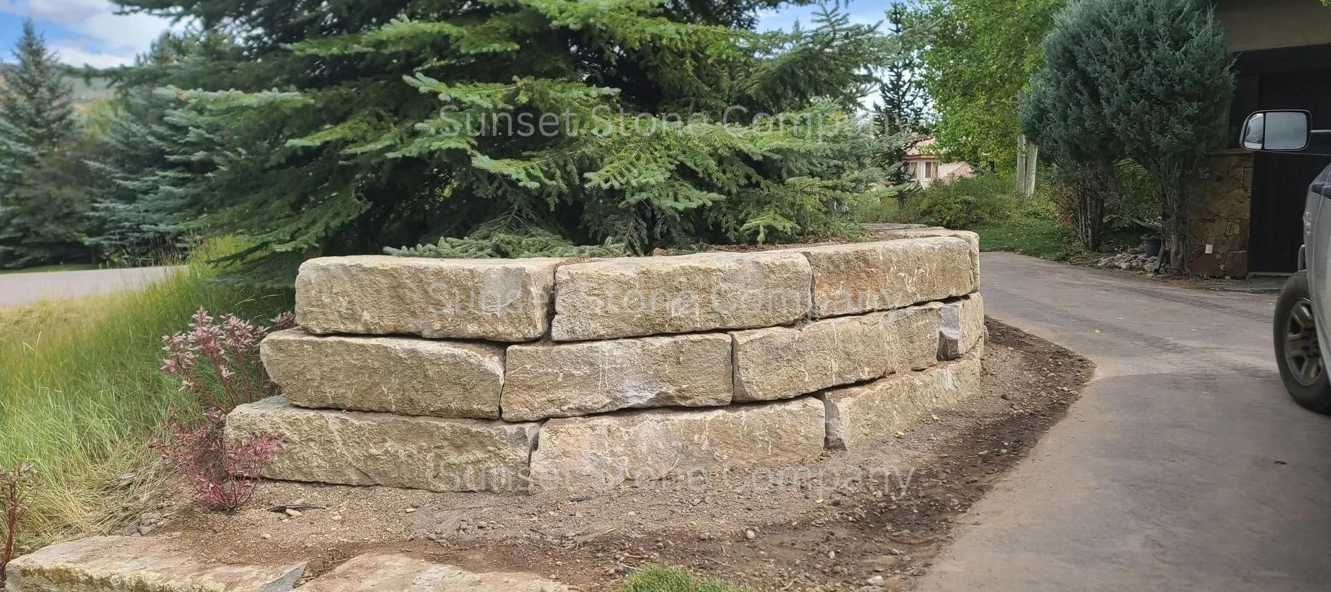 A large stone wall is sitting on the side of a road next to a garage