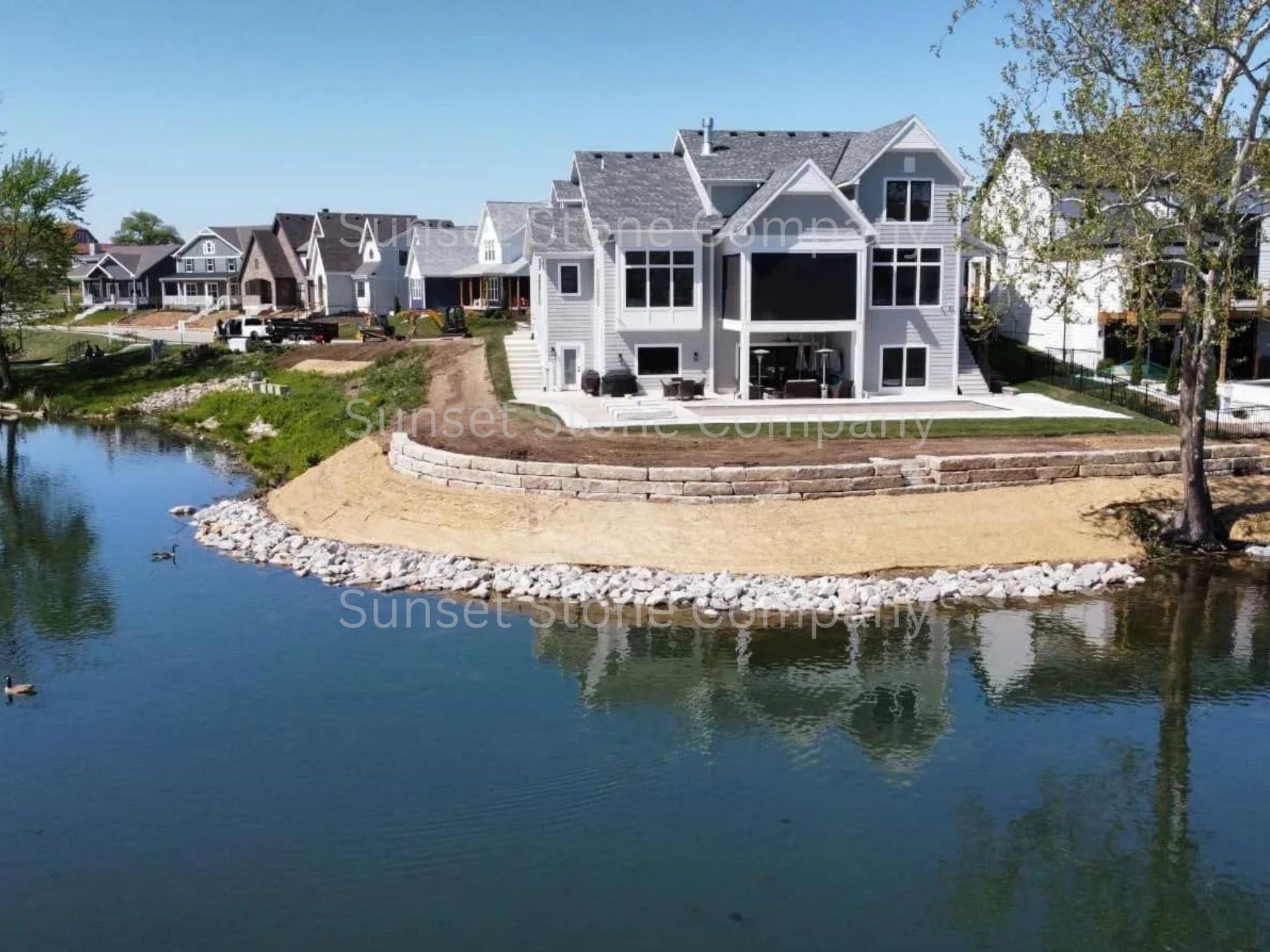 A large house sits on a small island in the middle of a lake