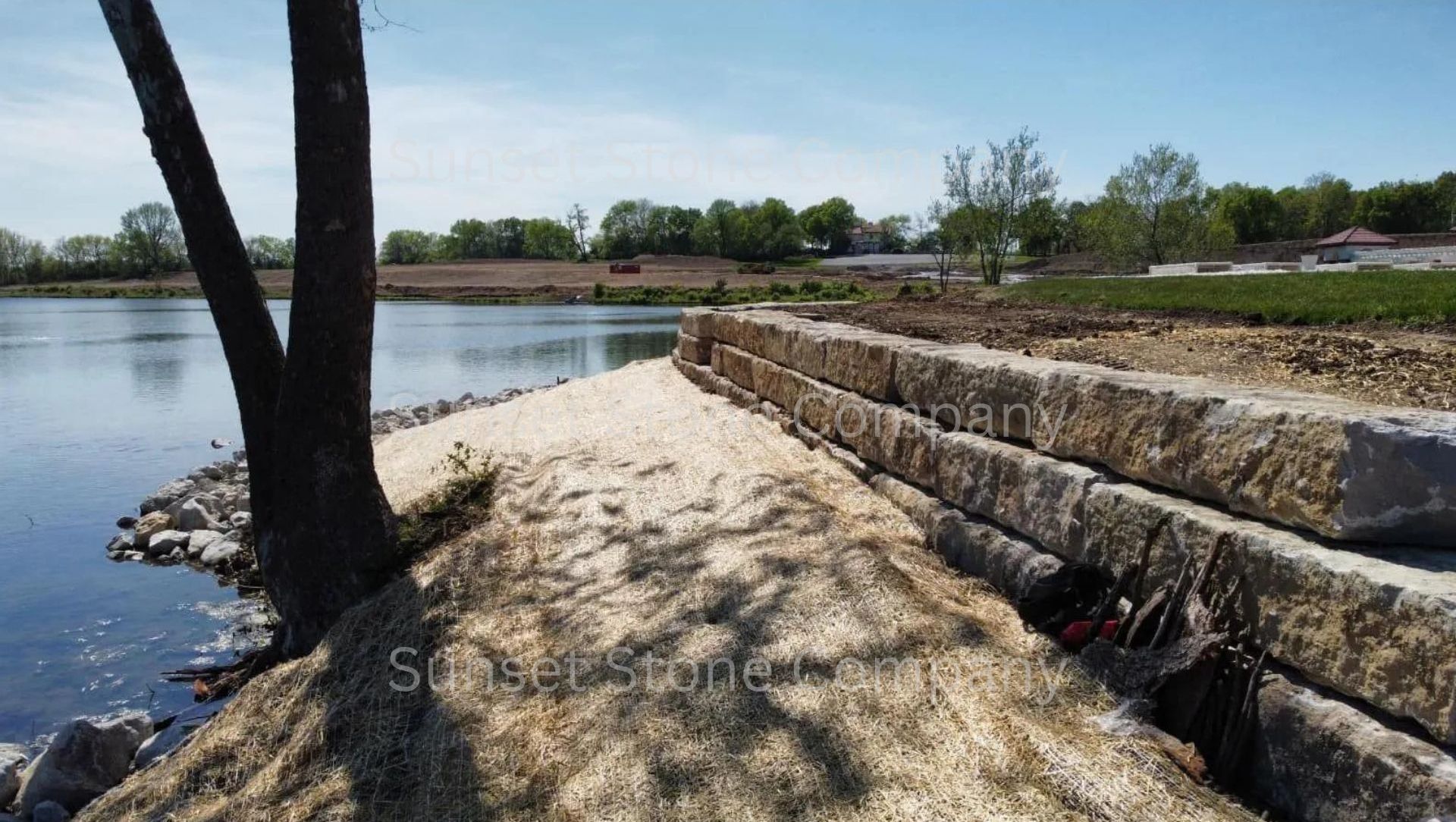A stone wall is being built on the shore of a lake