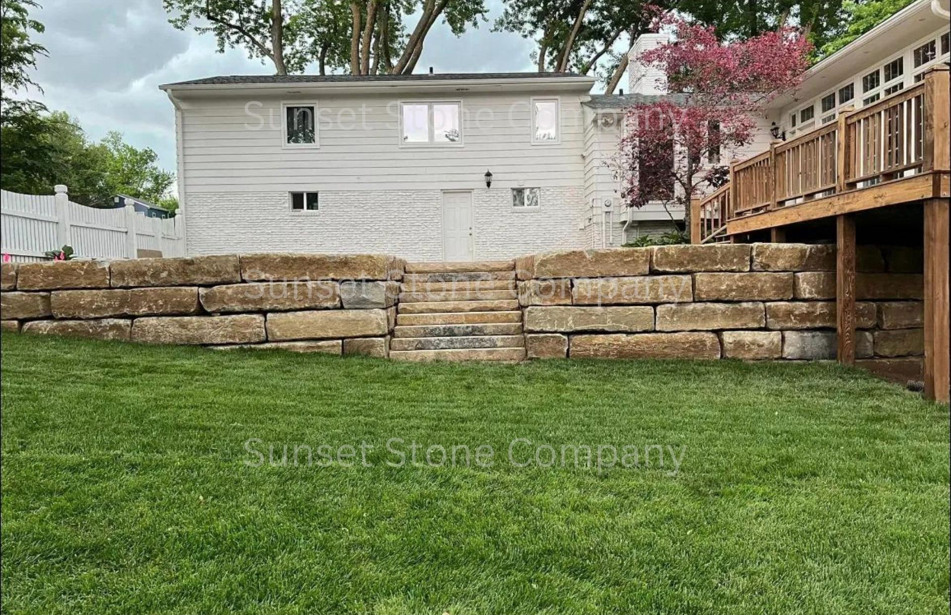 There is a large stone wall in the backyard of a house