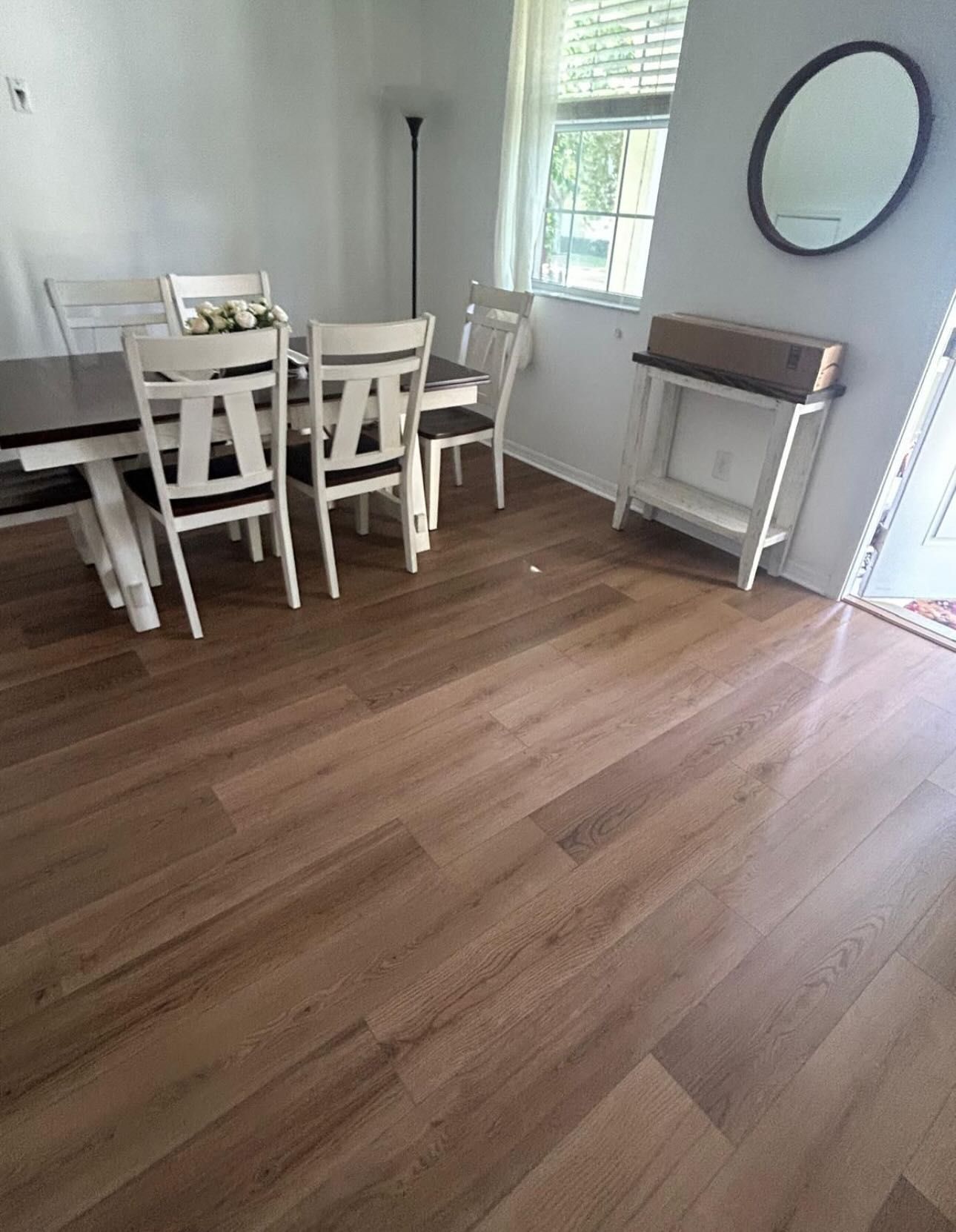 Dining room with a table, chairs, hardwood floors, a small table, a mirror, and a window.