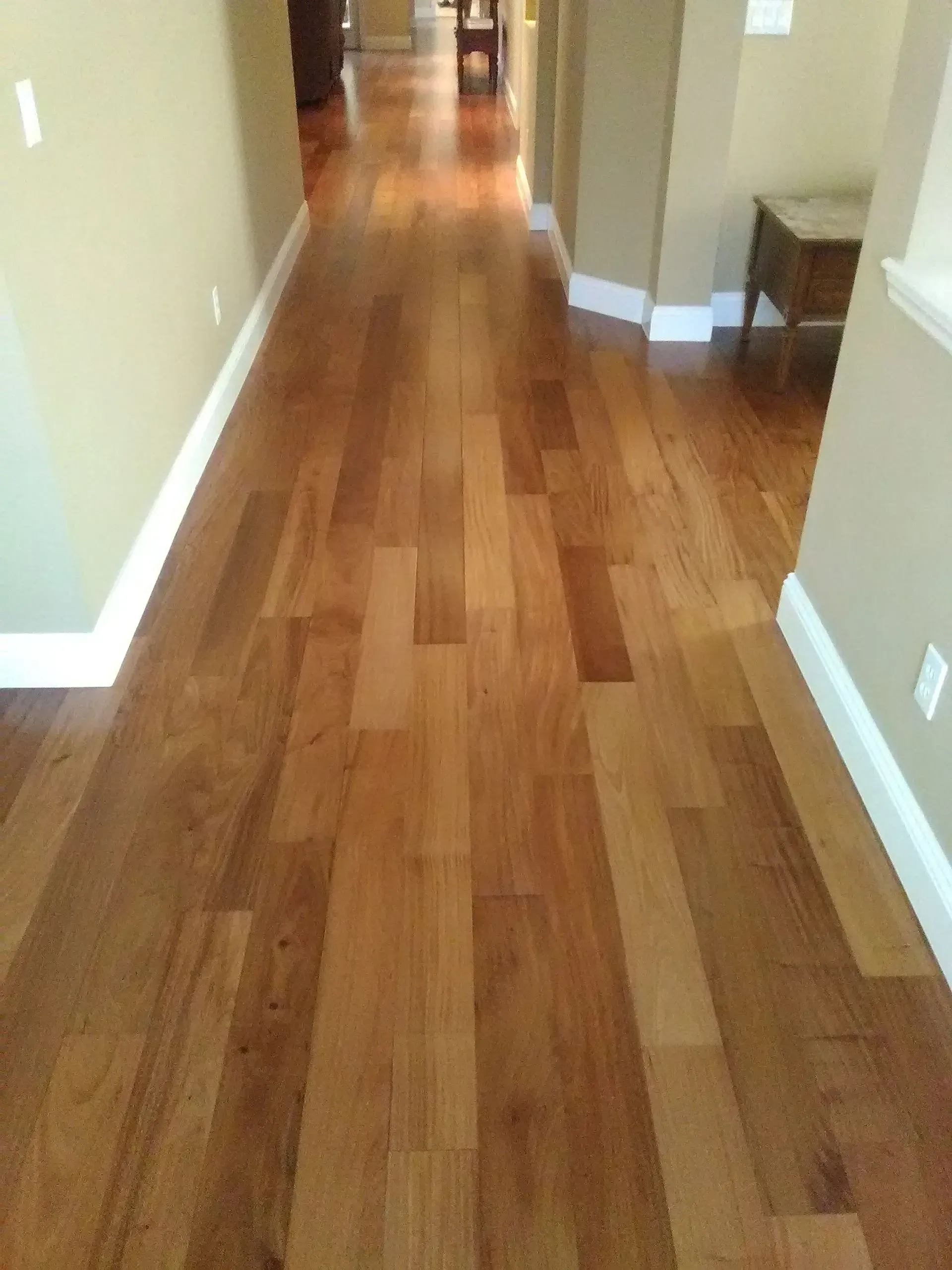 Wooden hallway with light brown floorboards and beige walls.
