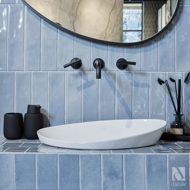 Modern bathroom with blue vertical tiles, white sink, black faucet and accessories.