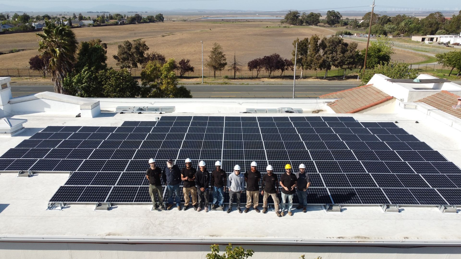 A group of people standing on top of a roof with solar panels.
