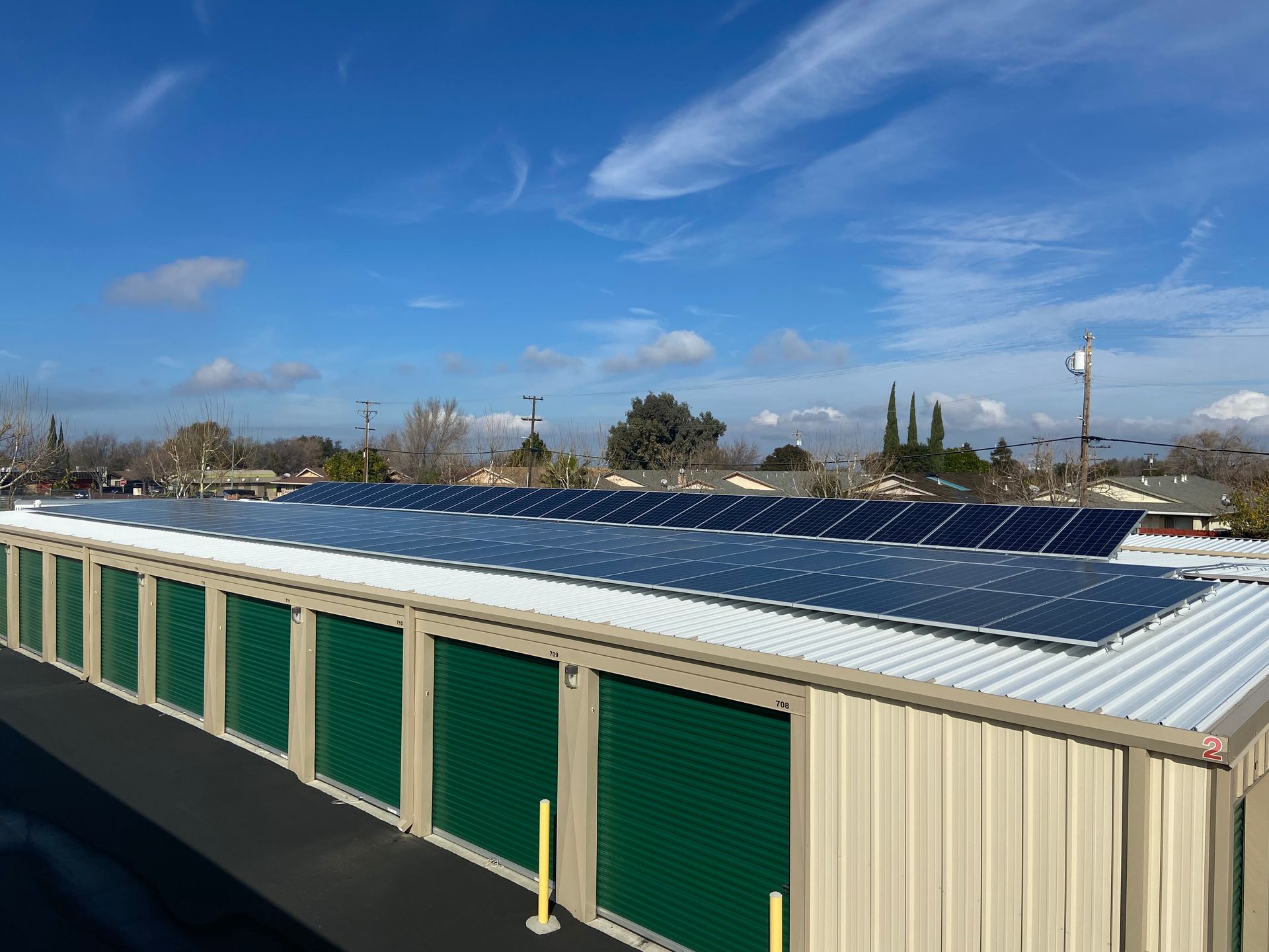 A storage building with green doors and solar panels on the roof.