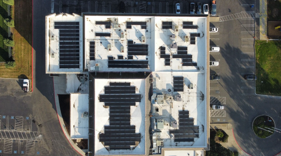 An aerial view of a building with solar panels on the roof.