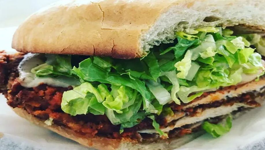 A close-up of a sandwich with lettuce and meat on a plate.