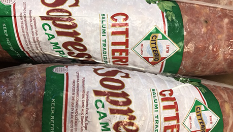 Two packages of sausage with green labels are sitting on a table.