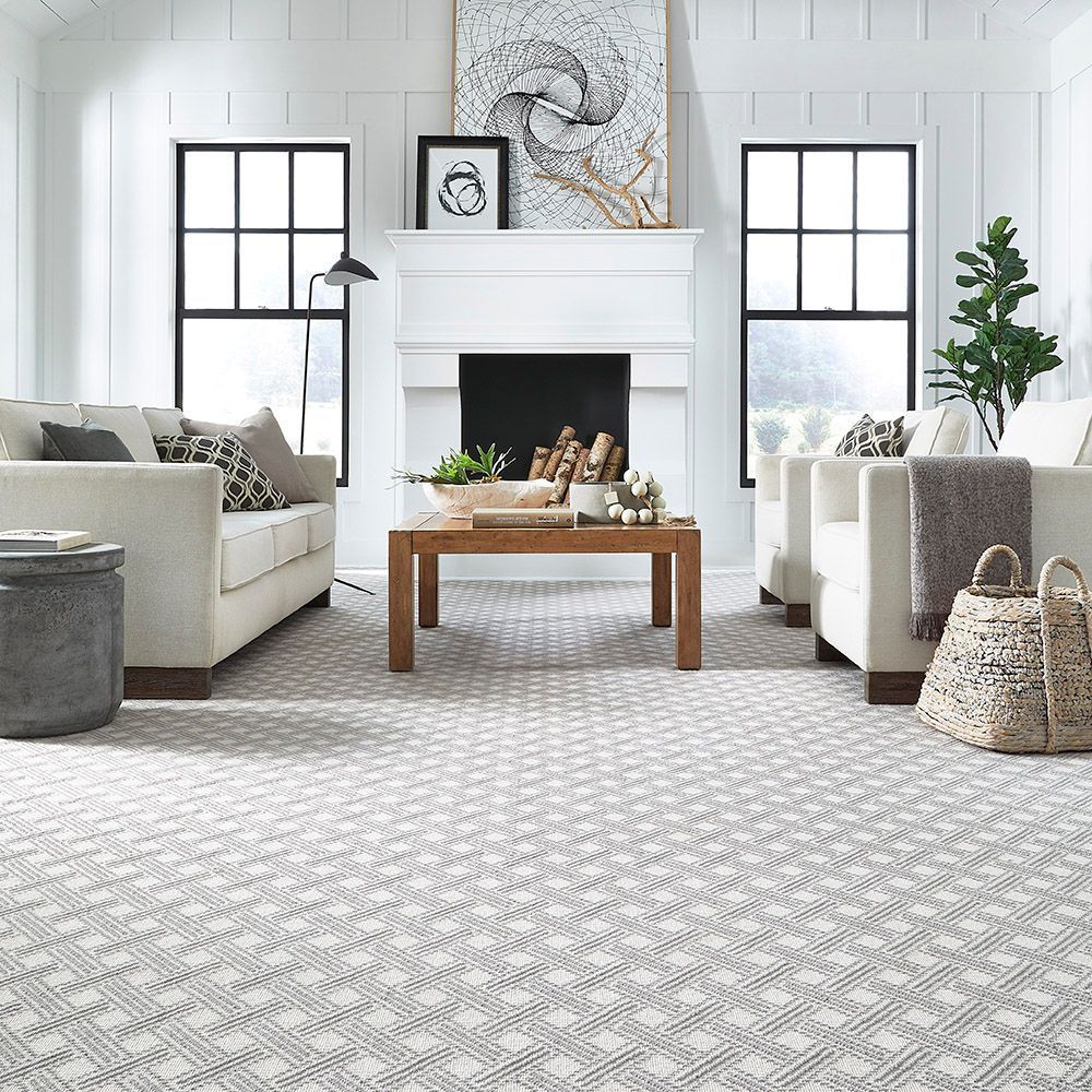Living room with neutral furniture, a patterned rug, a fireplace, and large windows.