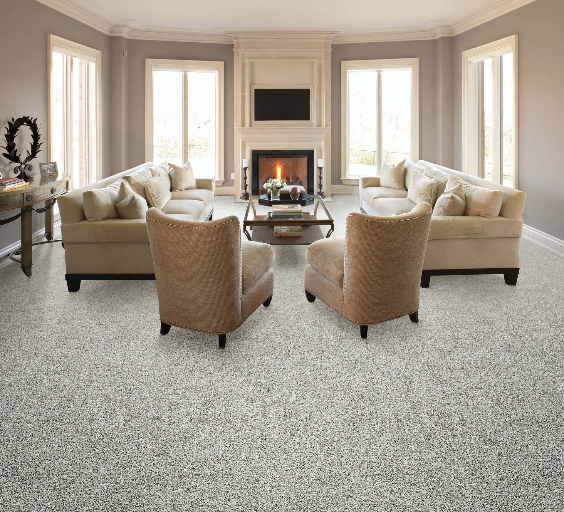 Living room with light-colored speckled flooring, beige sofas, armchairs, fireplace, and windows.