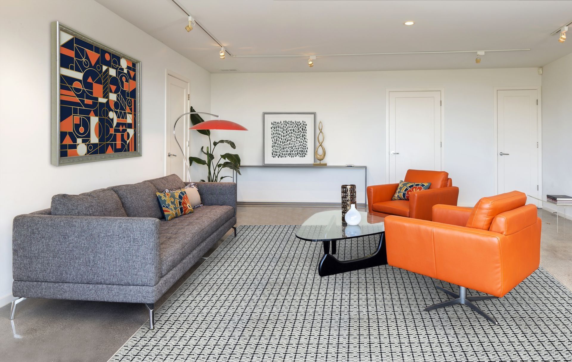 Modern living room with a gray couch, orange chairs, and abstract art.