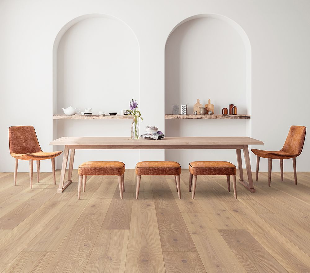 Dining room with wooden table, chairs, and benches on light wood floor; white arched shelves in background.