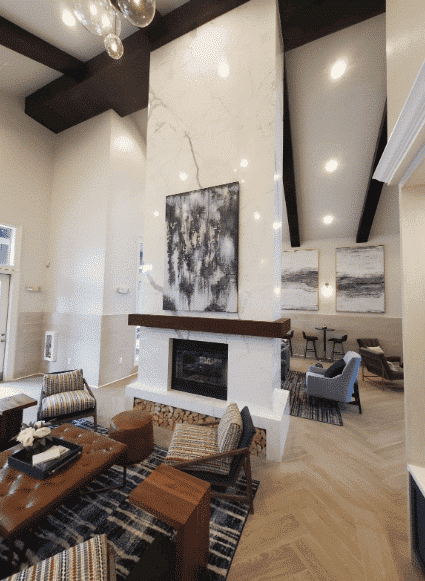 Living room with a fireplace, art, seating, and high ceilings.