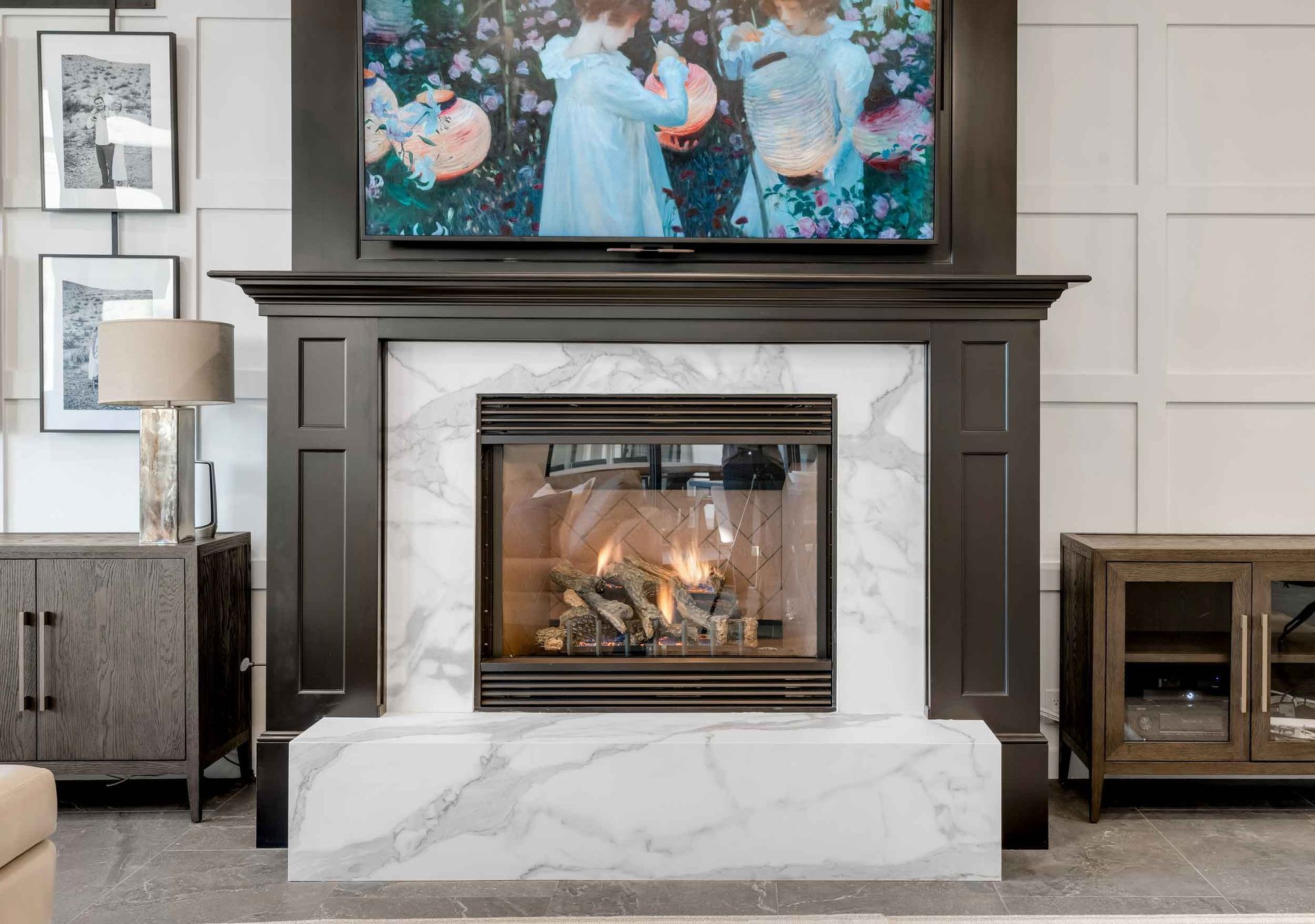 Fireplace with marble surround, black mantle, and a lit fire beneath a mounted TV.