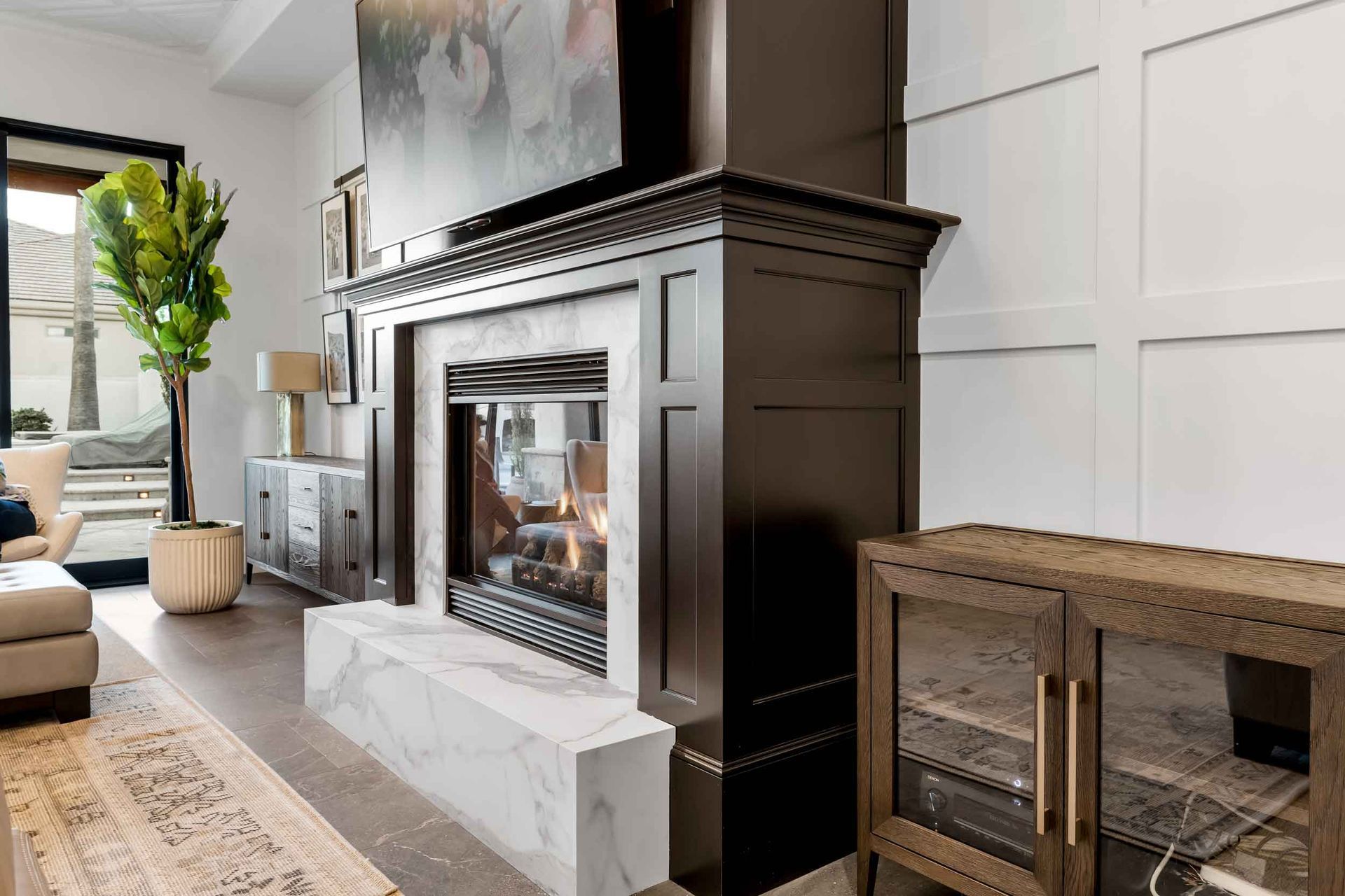 Living room with fireplace, TV, and decorative paneling. Dark wood mantel and marble hearth.