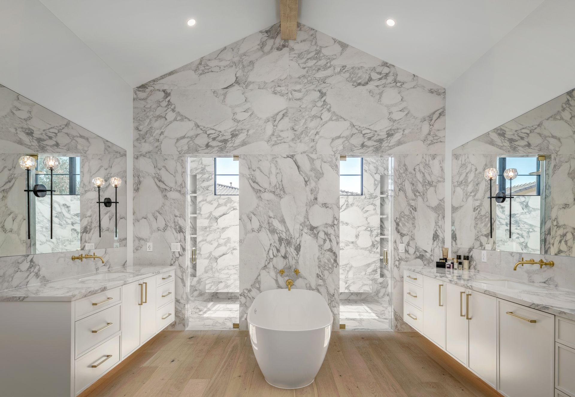 Luxurious bathroom with marble walls, dual sinks, and a freestanding tub.