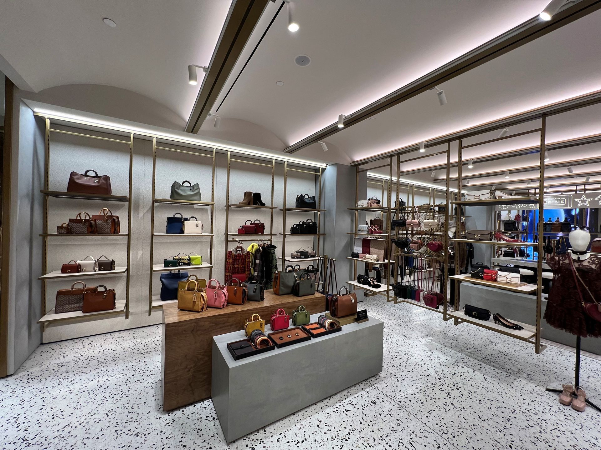 Interior of a luxury handbag store with shelves of colorful purses and a display table.
