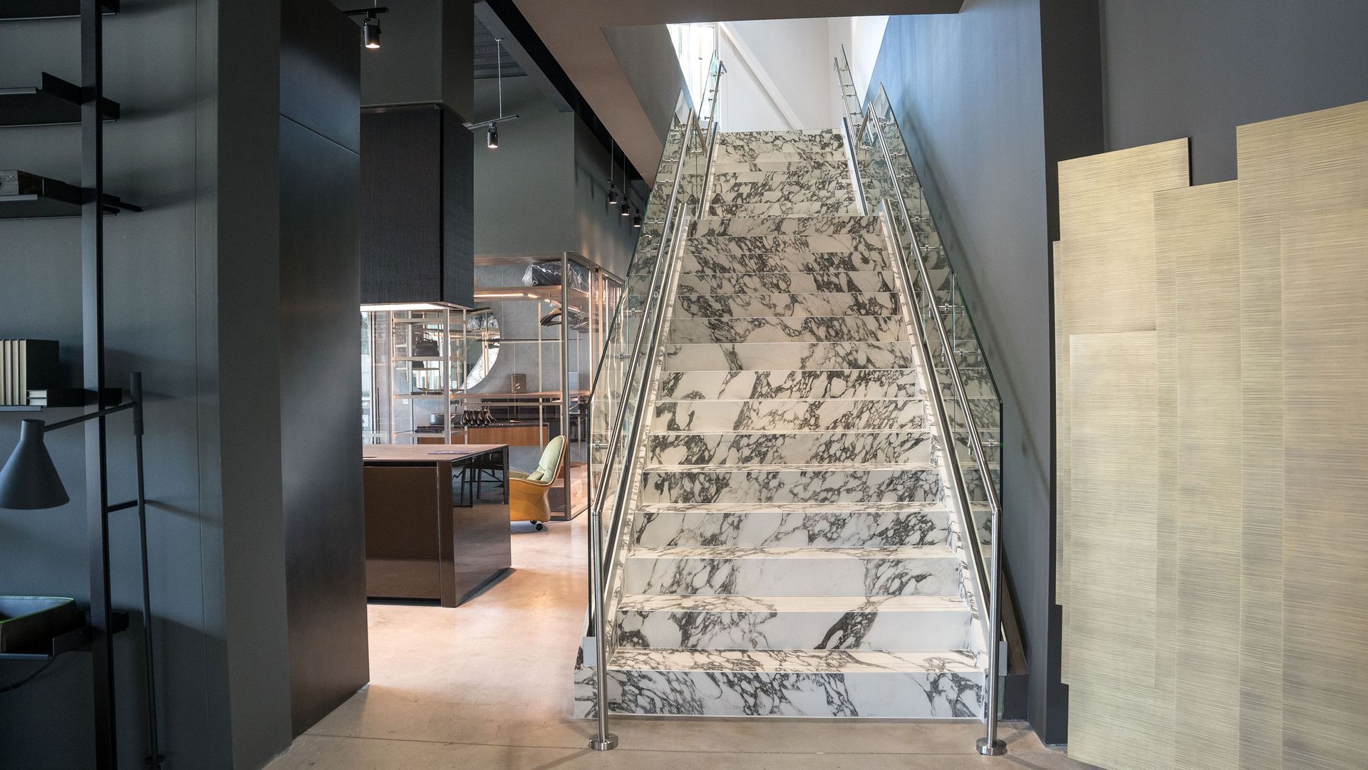 Staircase with marble steps and patterned railing inside a modern building, leading upwards.