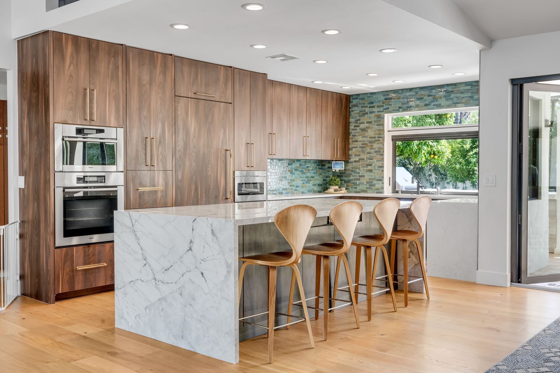 Modern kitchen with wood cabinets, marble island, and bar stools.