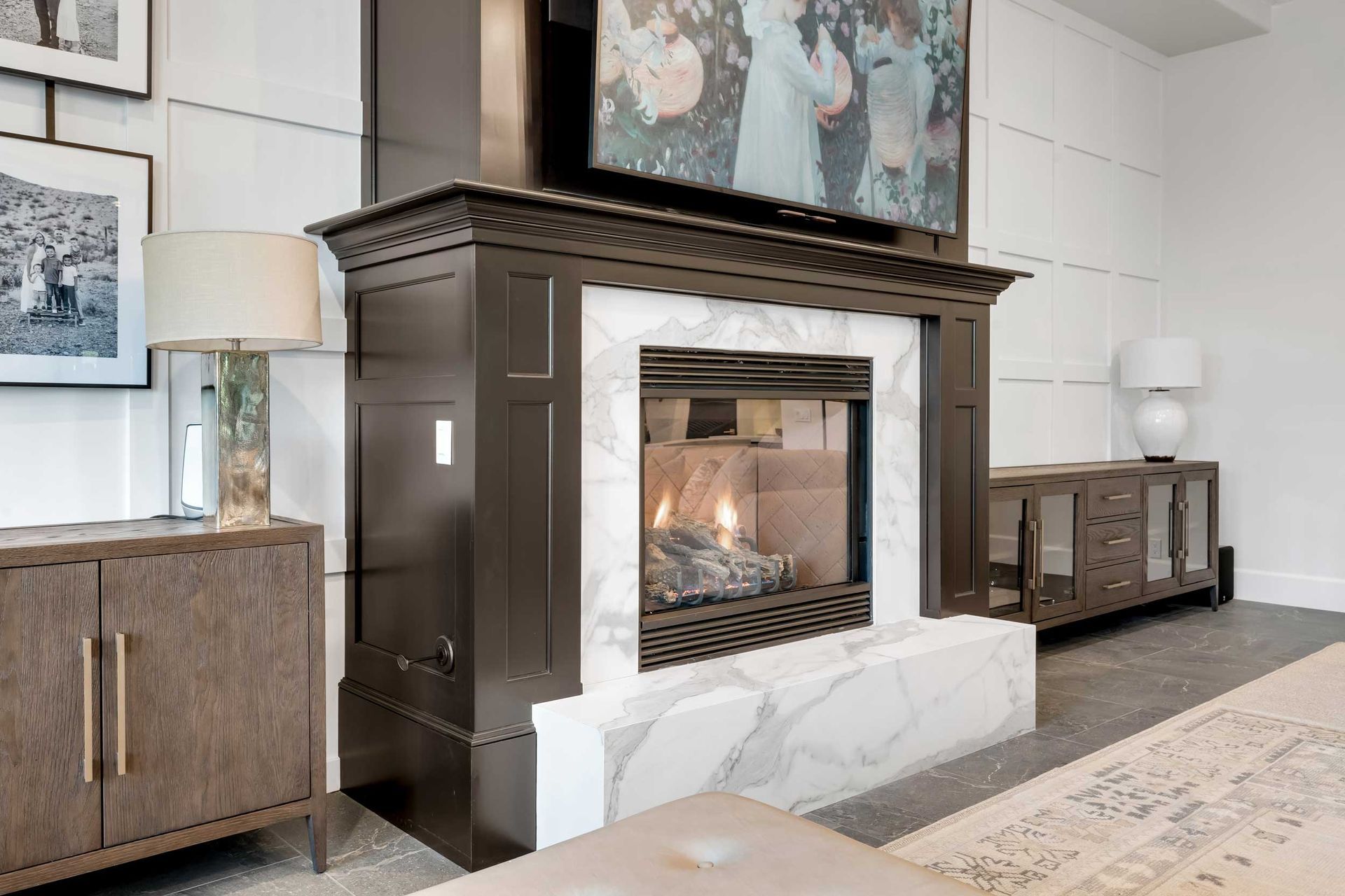 Fireplace with marble surround, dark brown trim, and a lit fire in a modern living room.