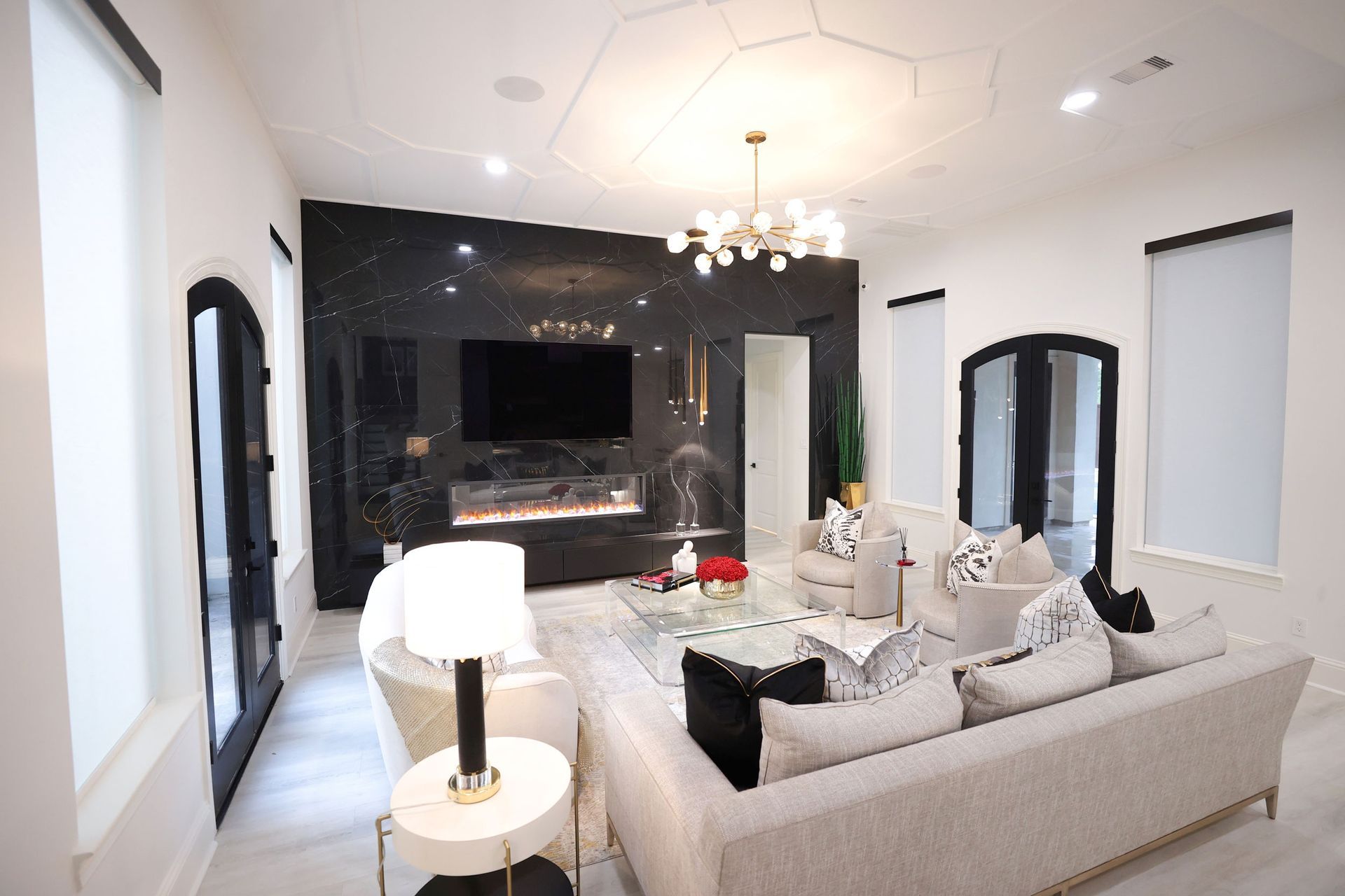 Luxurious living room with black marble fireplace, cream sofa, and modern chandelier.
