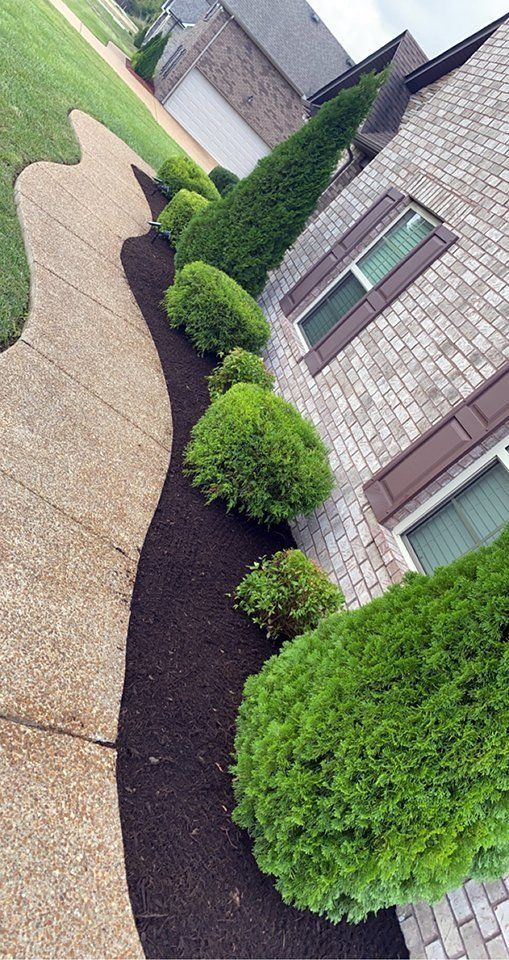 A brick house with a landscaped bed of shrubs and a walkway.