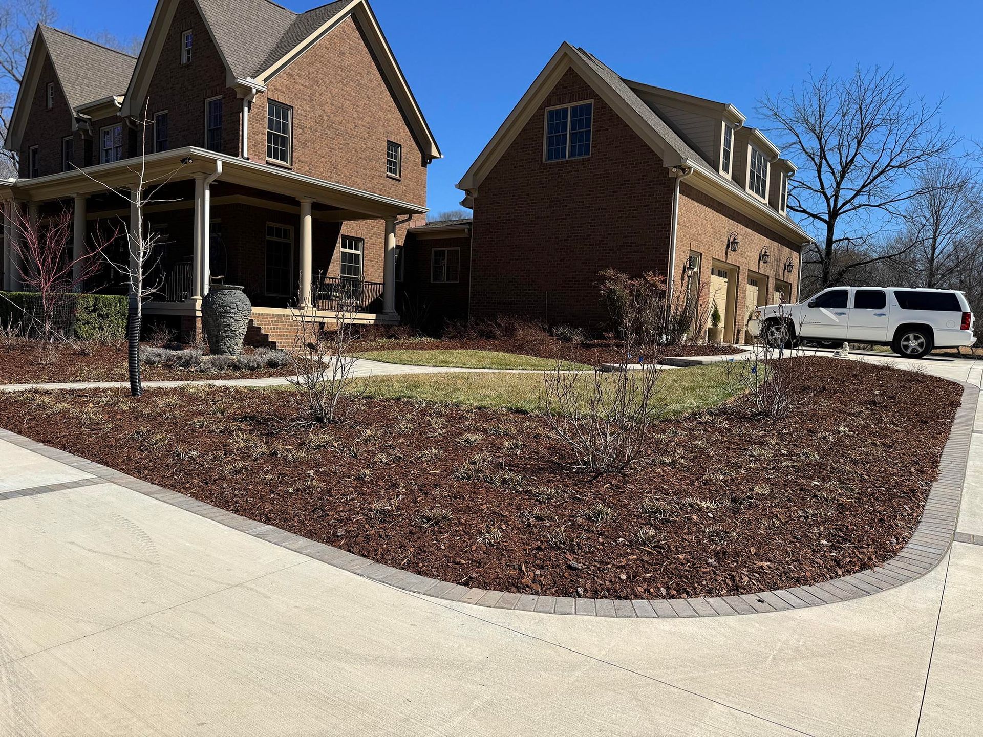 Brick houses with a landscaped yard and a white SUV.