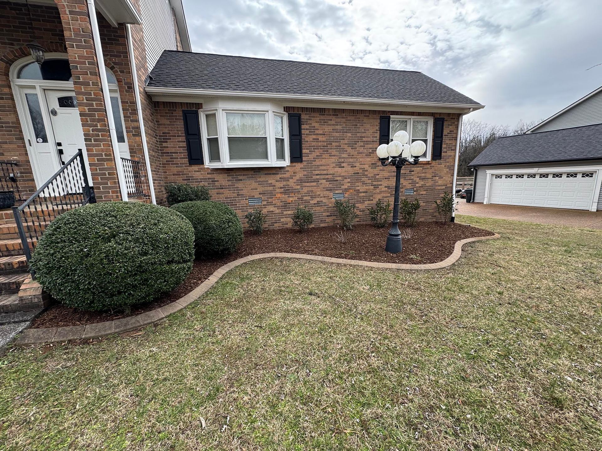 Brick house exterior with manicured landscaping and lawn; cloudy sky.