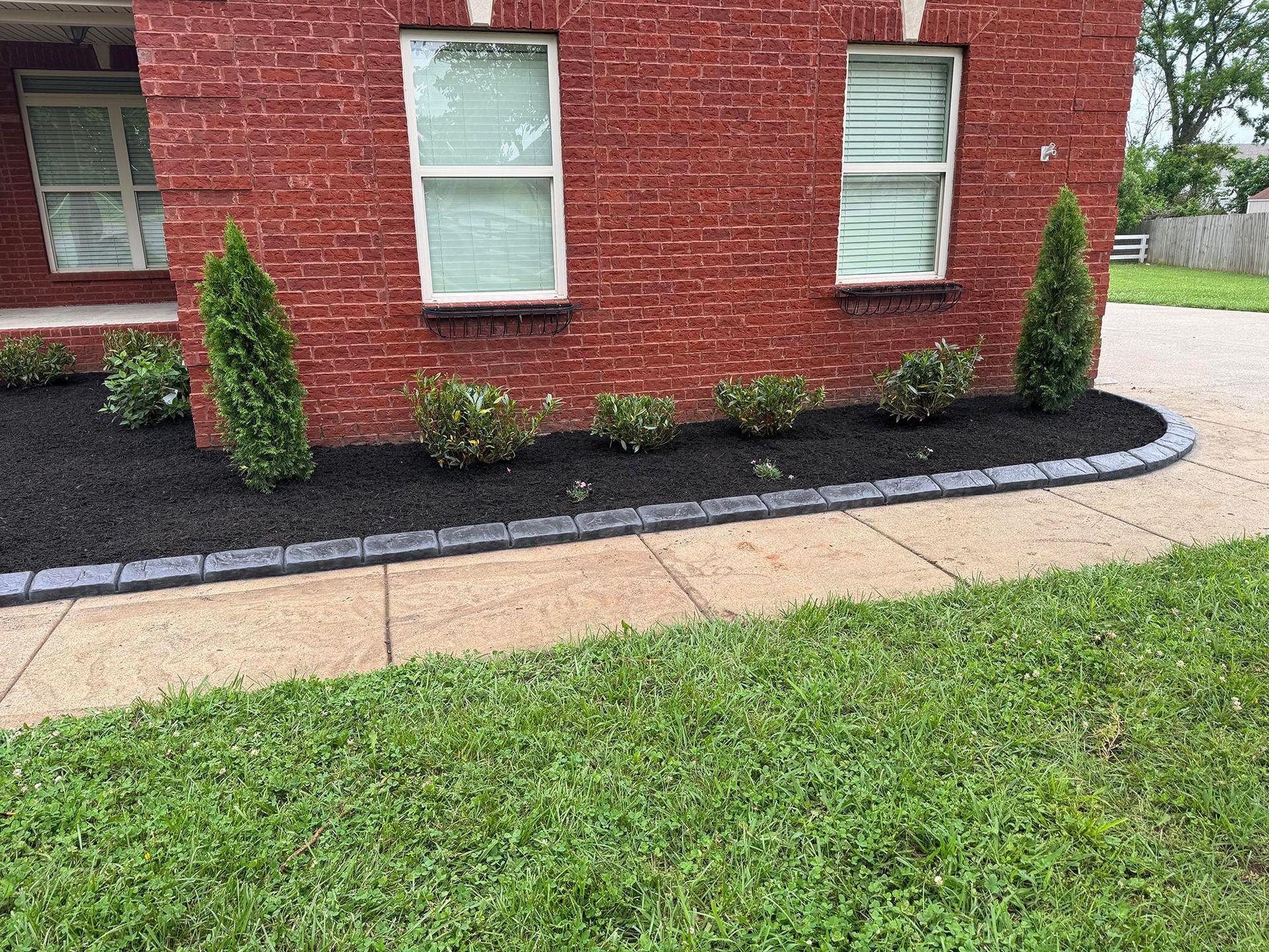 Brick building with landscaped flower bed, dark mulch, and green lawn.