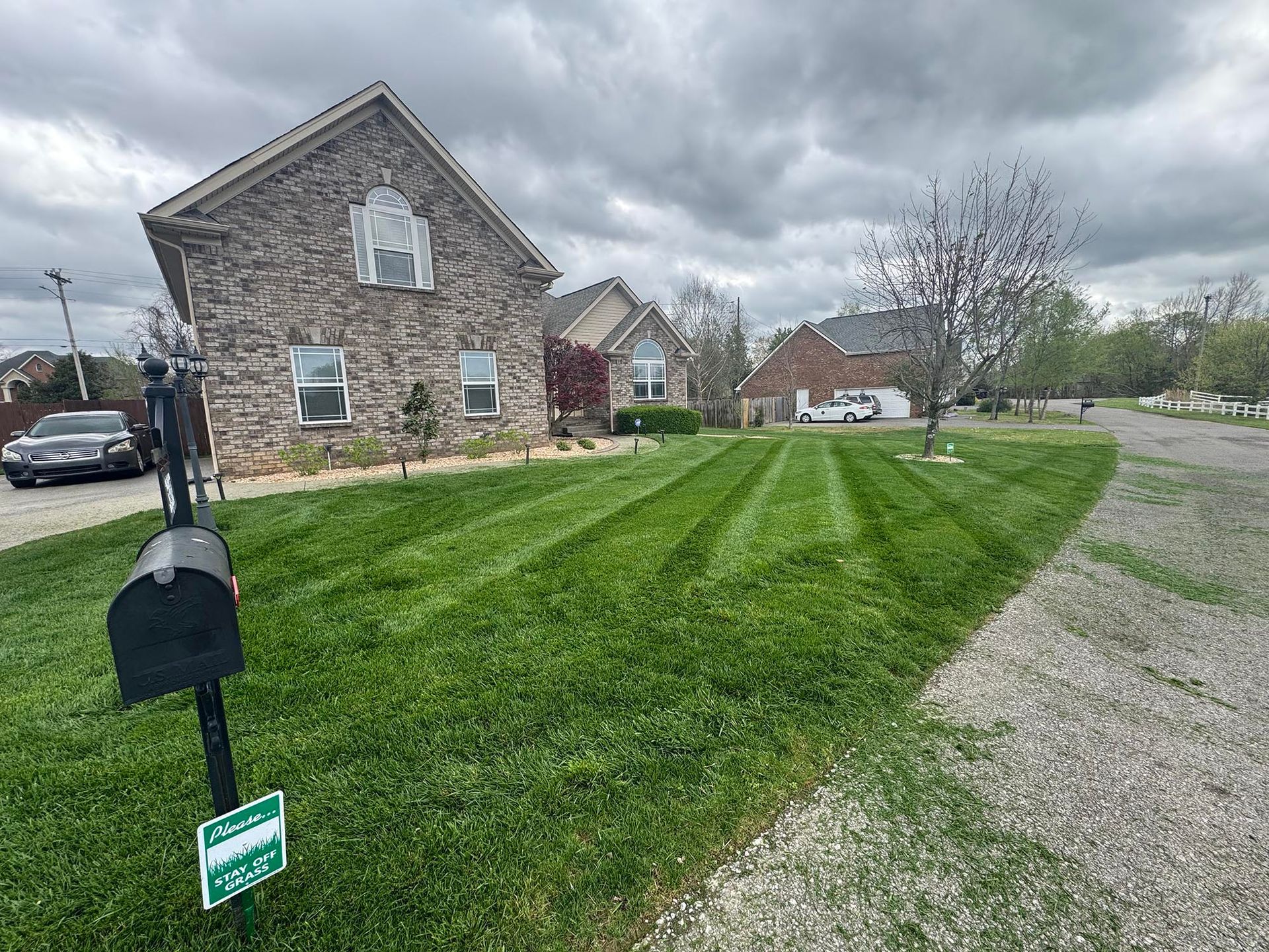 House with freshly mowed lawn, dark clouds overhead. Black mailbox in foreground.